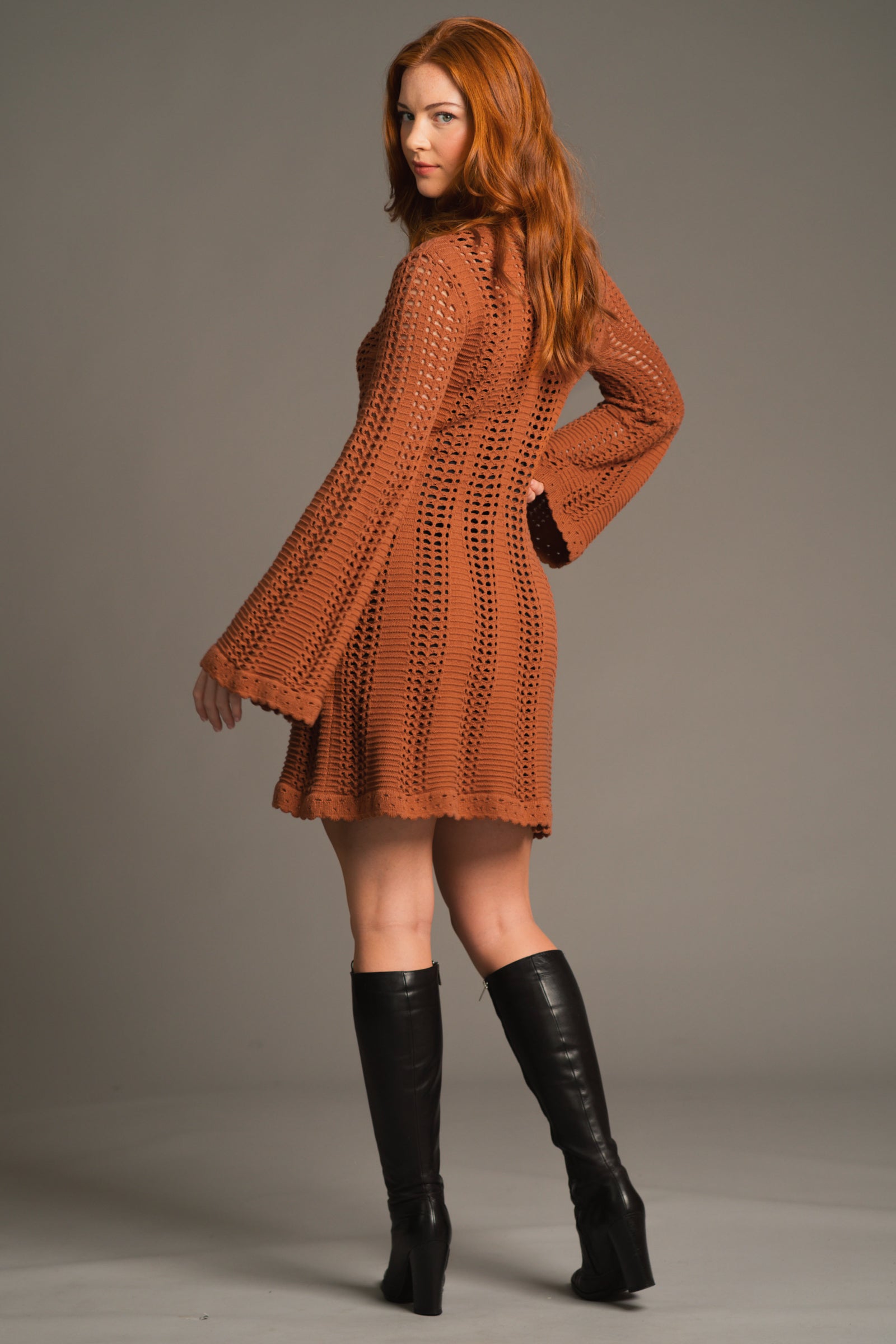 Back view of Anna in Marianne Rust midi crochet style Knit Dress Styled with black knee high boots