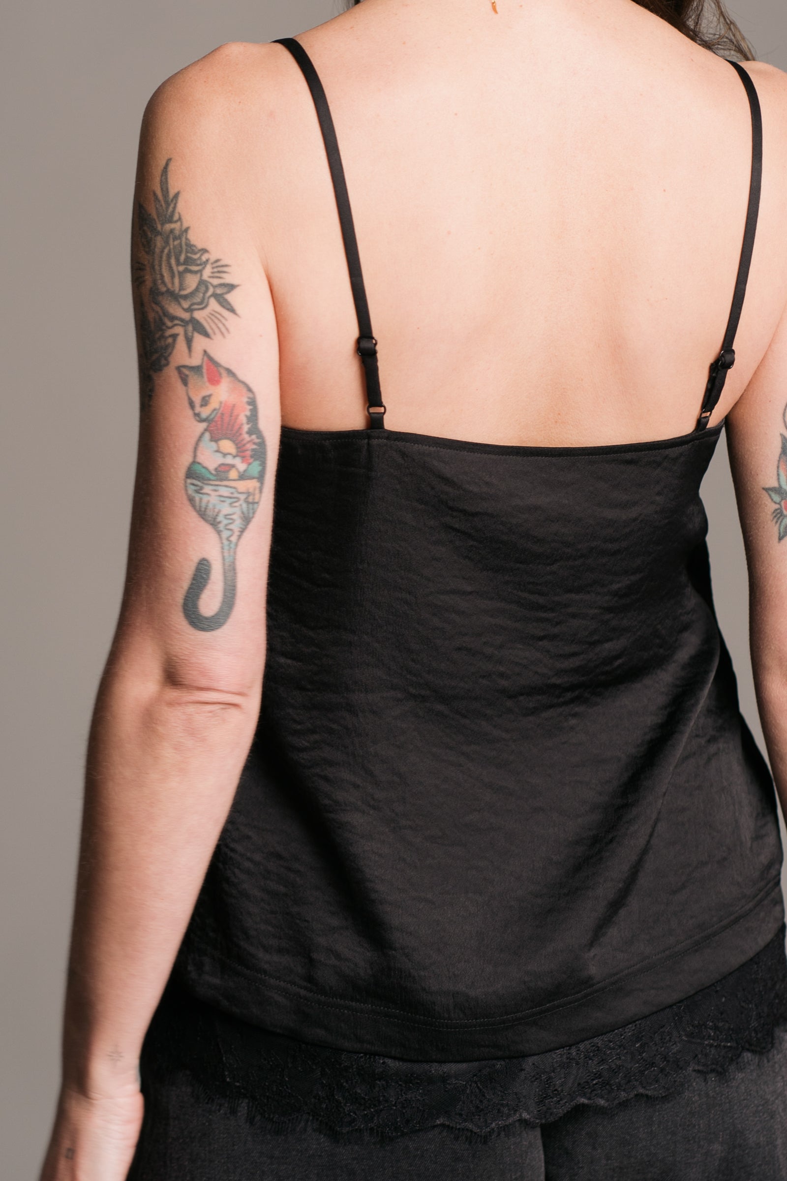 Little Lies Nightbird black cami top with lace trim – back view showing adjustable straps and layered detail over distressed denim