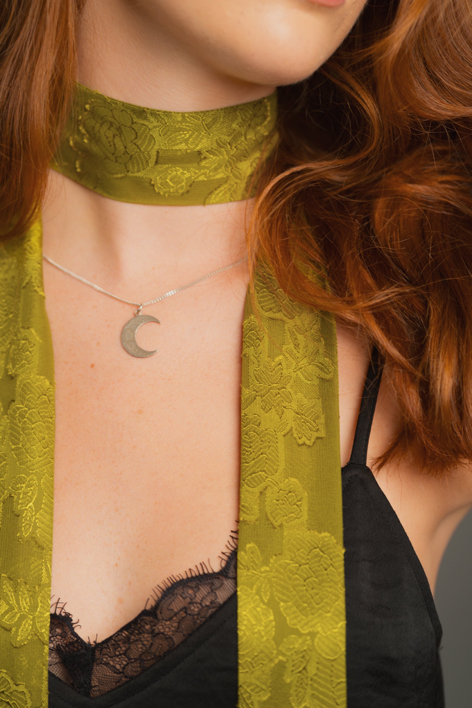 Close-up fabric detail shot of Olive Skinny scarf styles with Crescent moon necklace and nightbird black cami top.