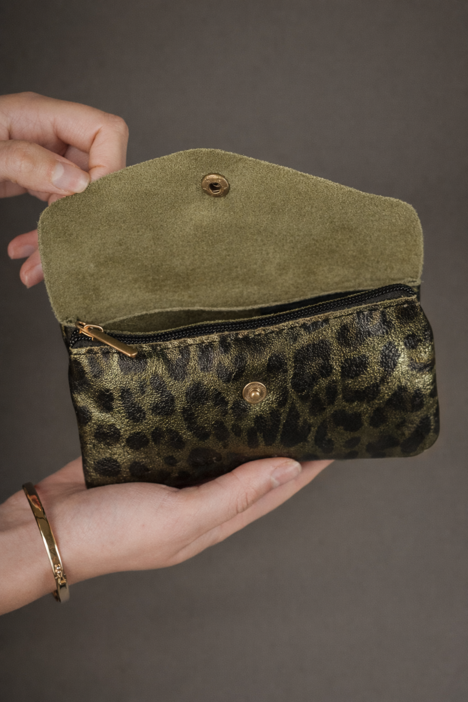 Olive metallic genuine suede purse with leopard print opened to show suede lining and zip compartment, held in hands.