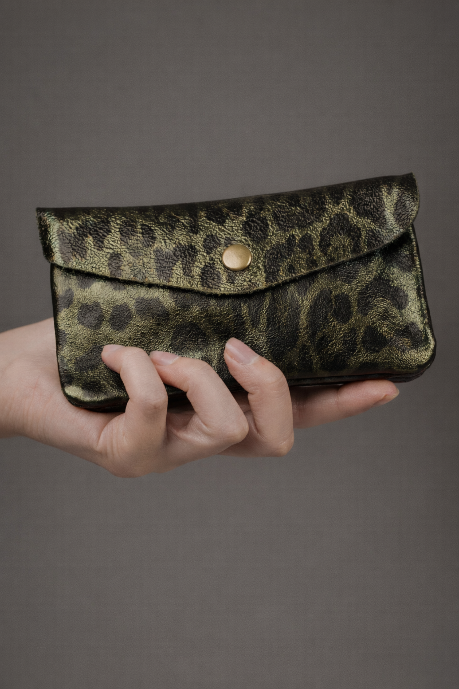 Olive metallic genuine suede purse with leopard print pattern held in a hand.