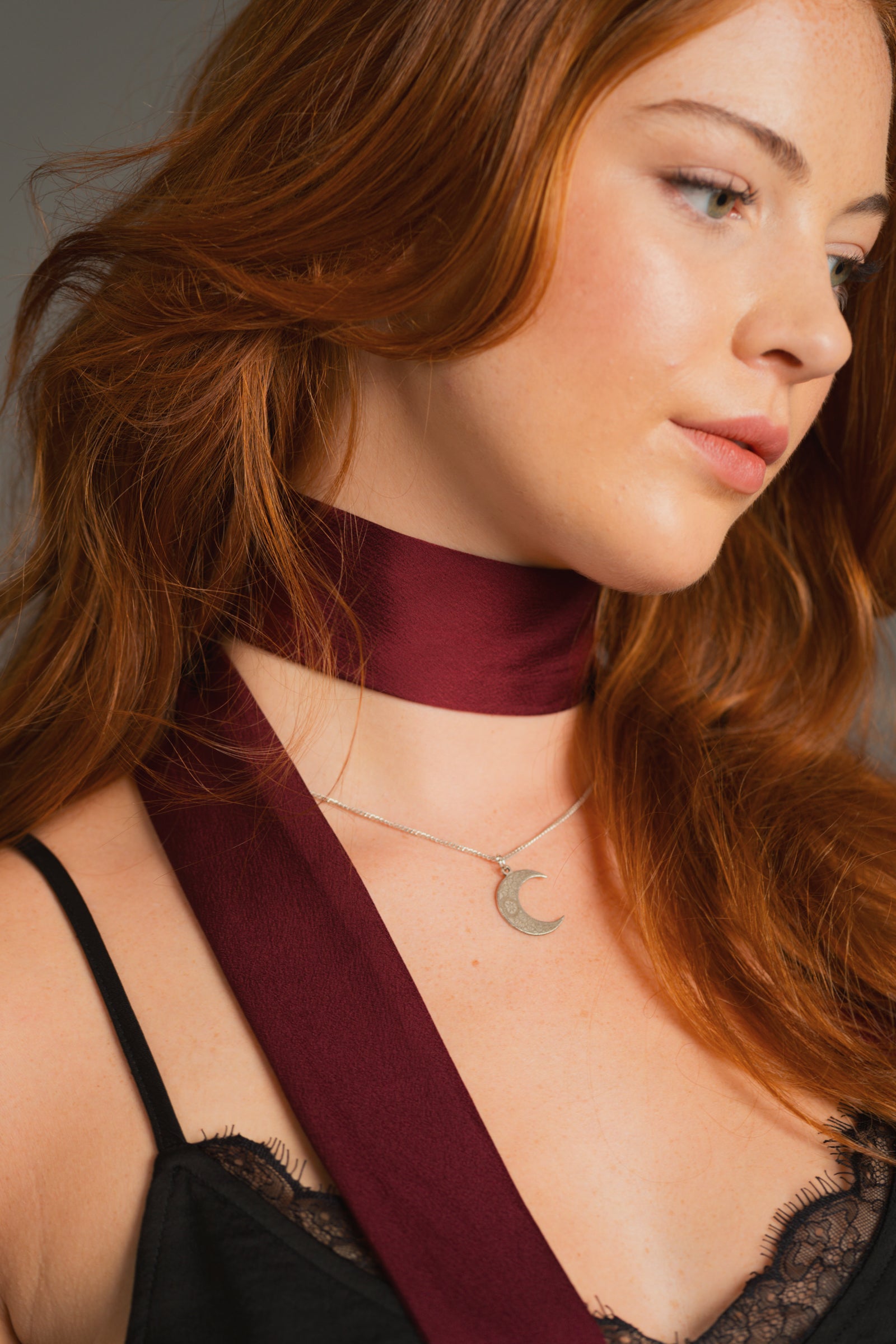 Close-up of plum skinny scarf wrapped around neck showing hammered satin texture.