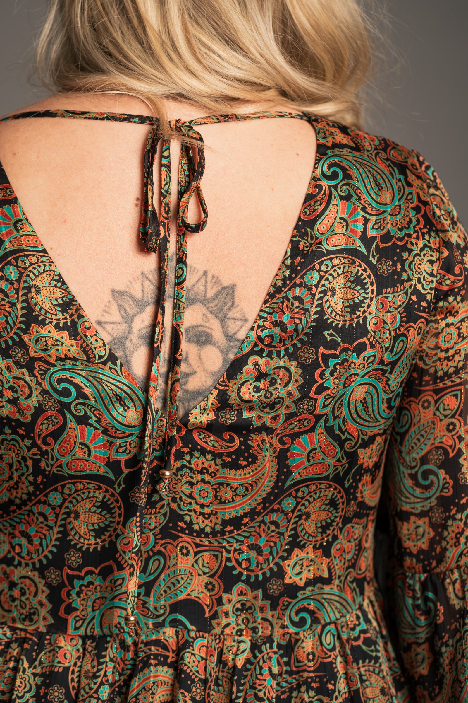 Close-up of Little Lies Ringo smock dress back with gold beaded tie neckline detail and flowing paisley print fabric