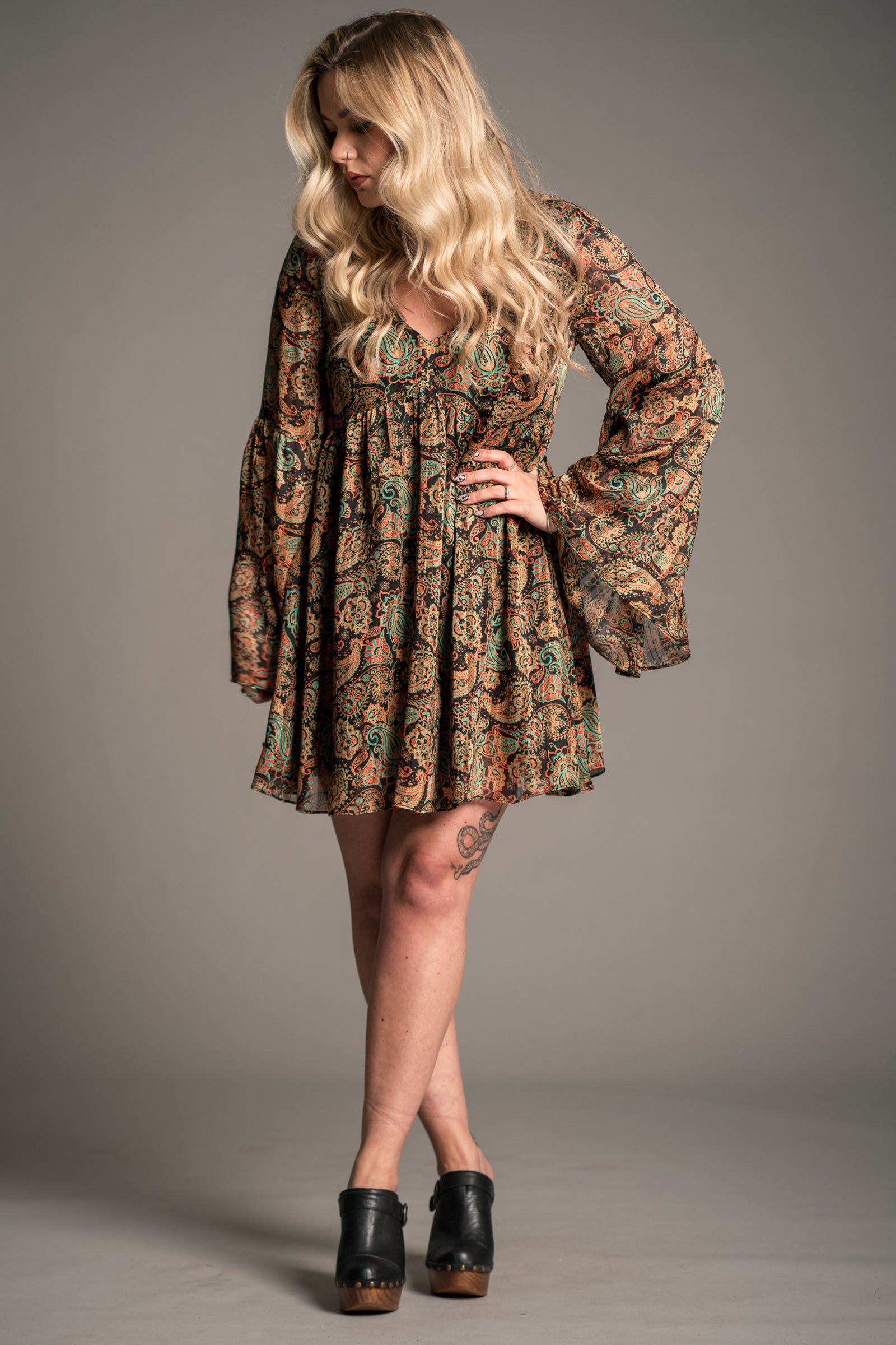 Model wearing Little Lies Ringo paisley smock dress with long flared sleeves styled with platform clogs for relaxed boho everyday outfit