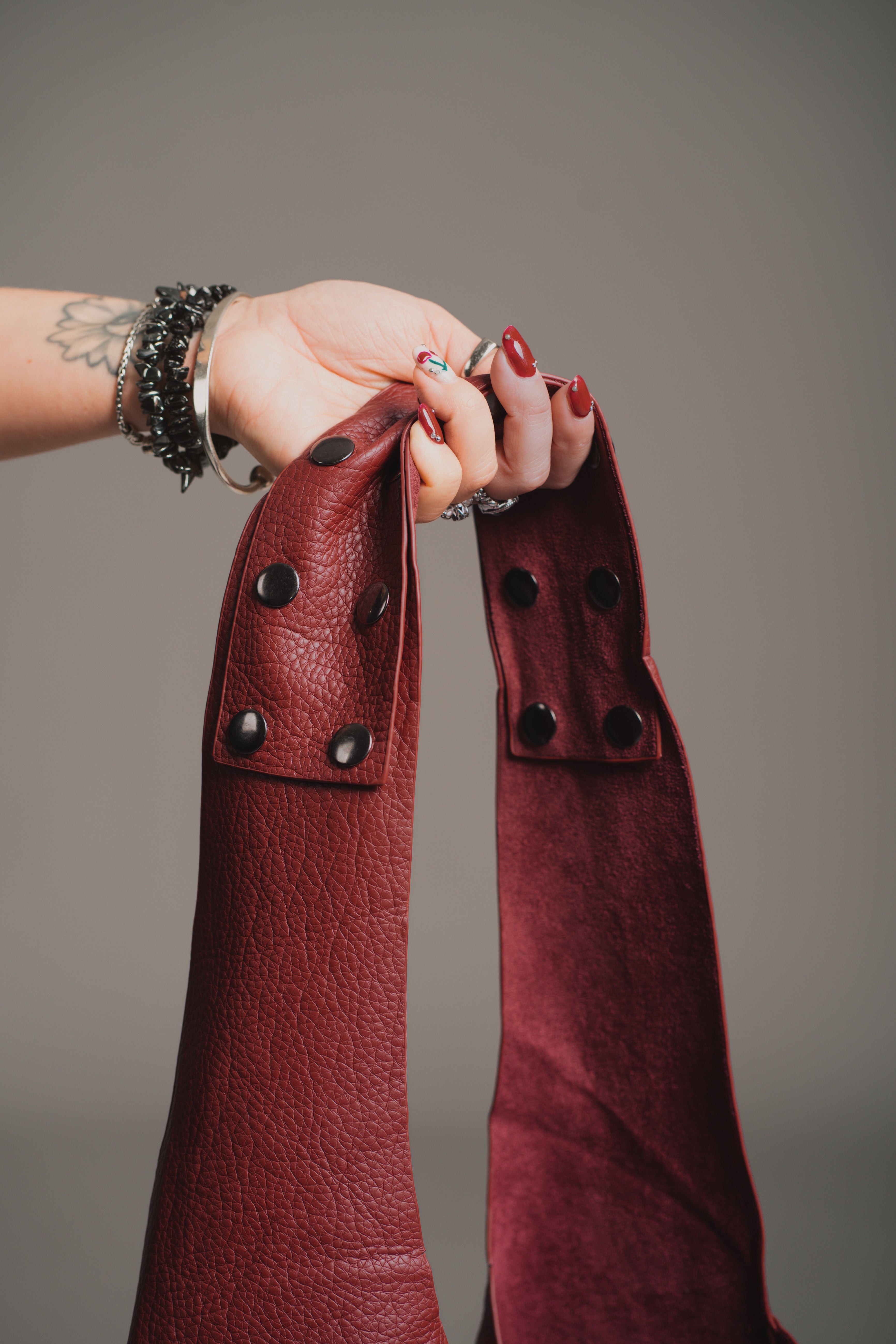 Model holding the Romy Studded Faux Leather Hobo Bag against a gray background