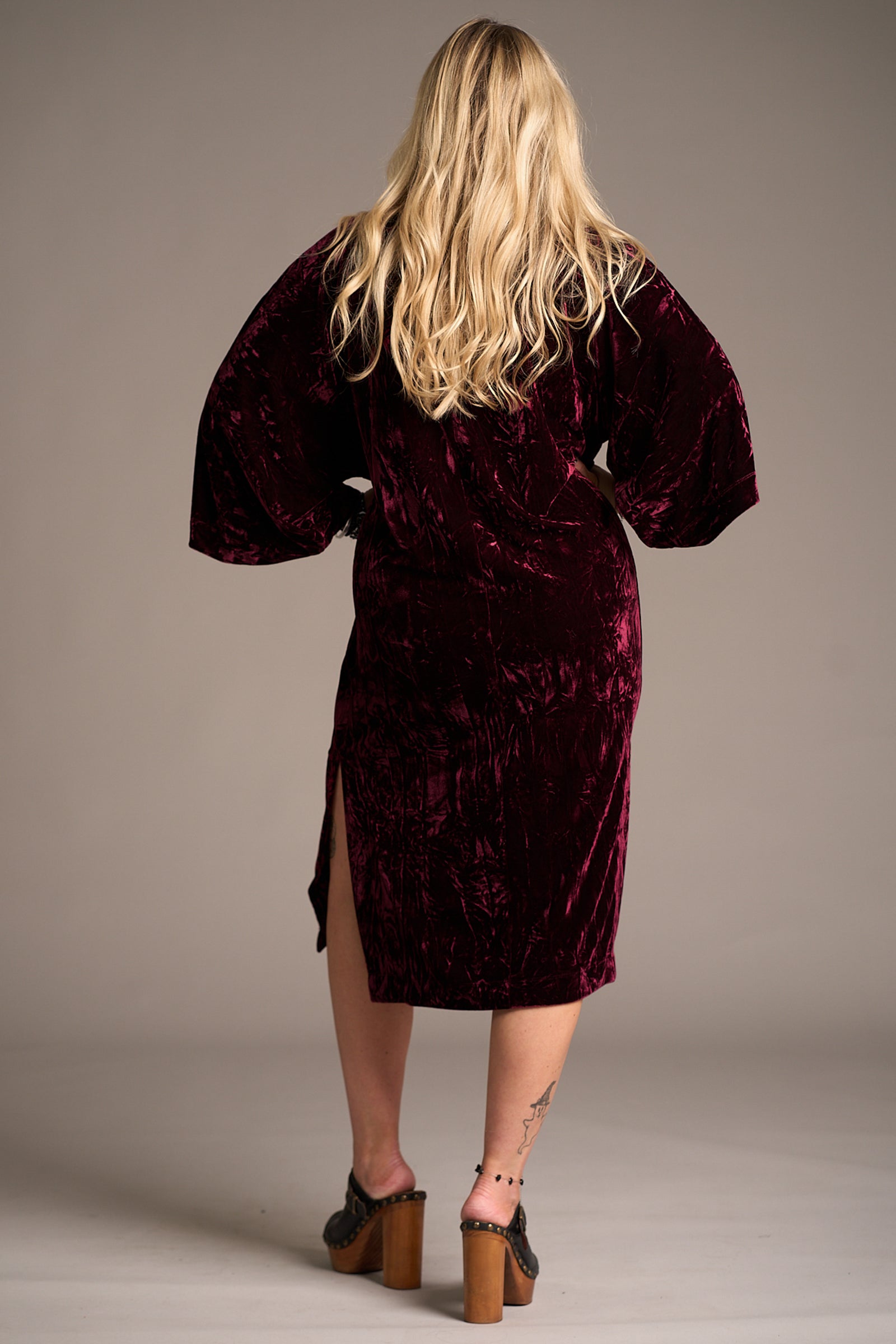 Erin showing the back of the Rumours Merlot Velvet Midi Dress, side split detail. Stevie Nicks inspired styling studio
