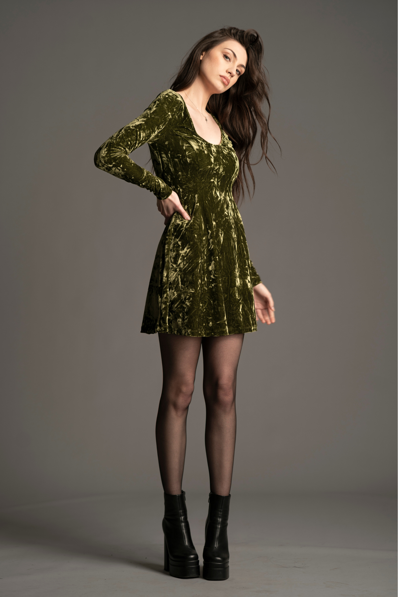 Andie wearing the Sweet Jane Olive Crushed velvet dress, as worn by Taylor Swift, against a gray background