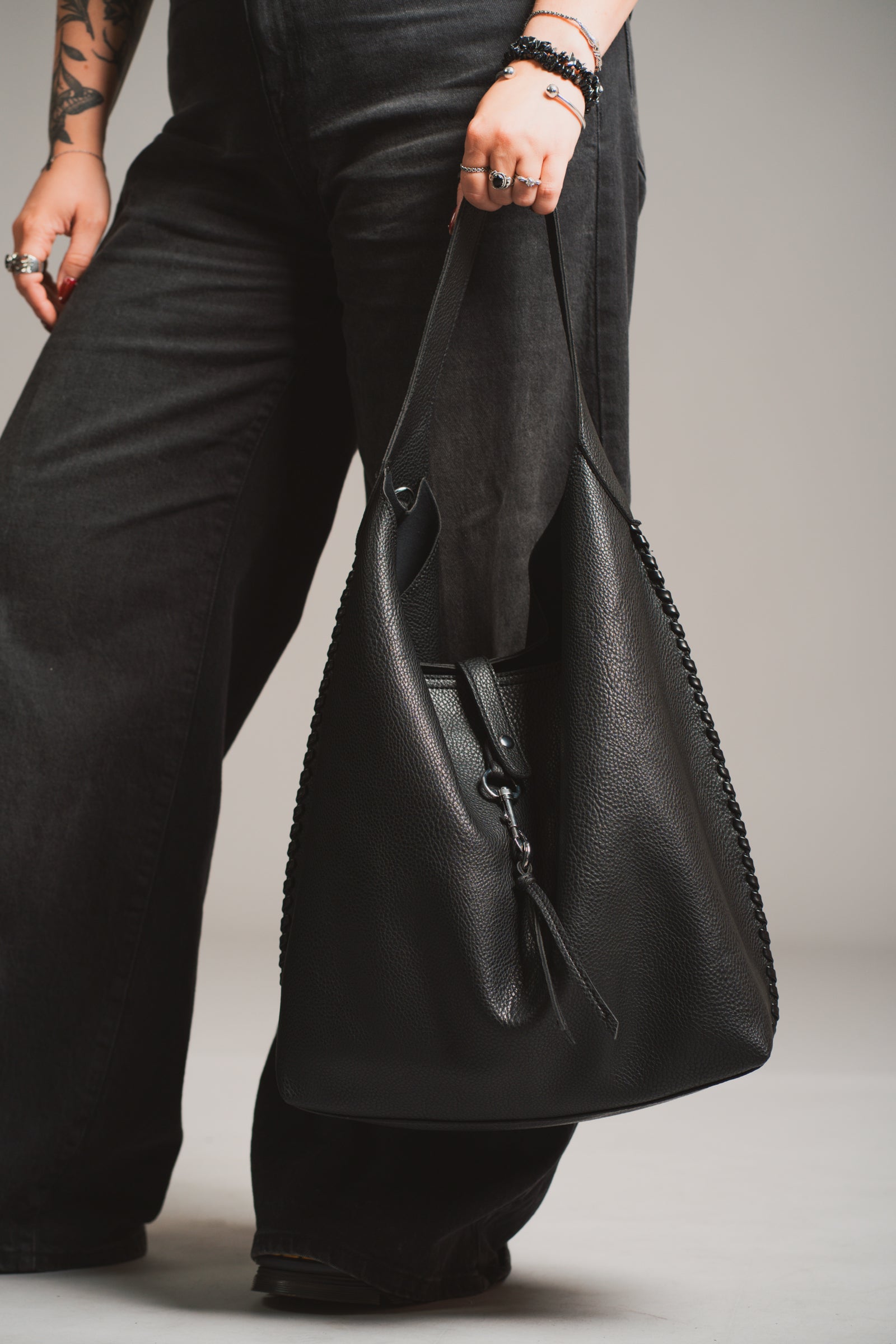 Model holding the Sadie Boho Hobo Faux Leather black bag, in studio shot.