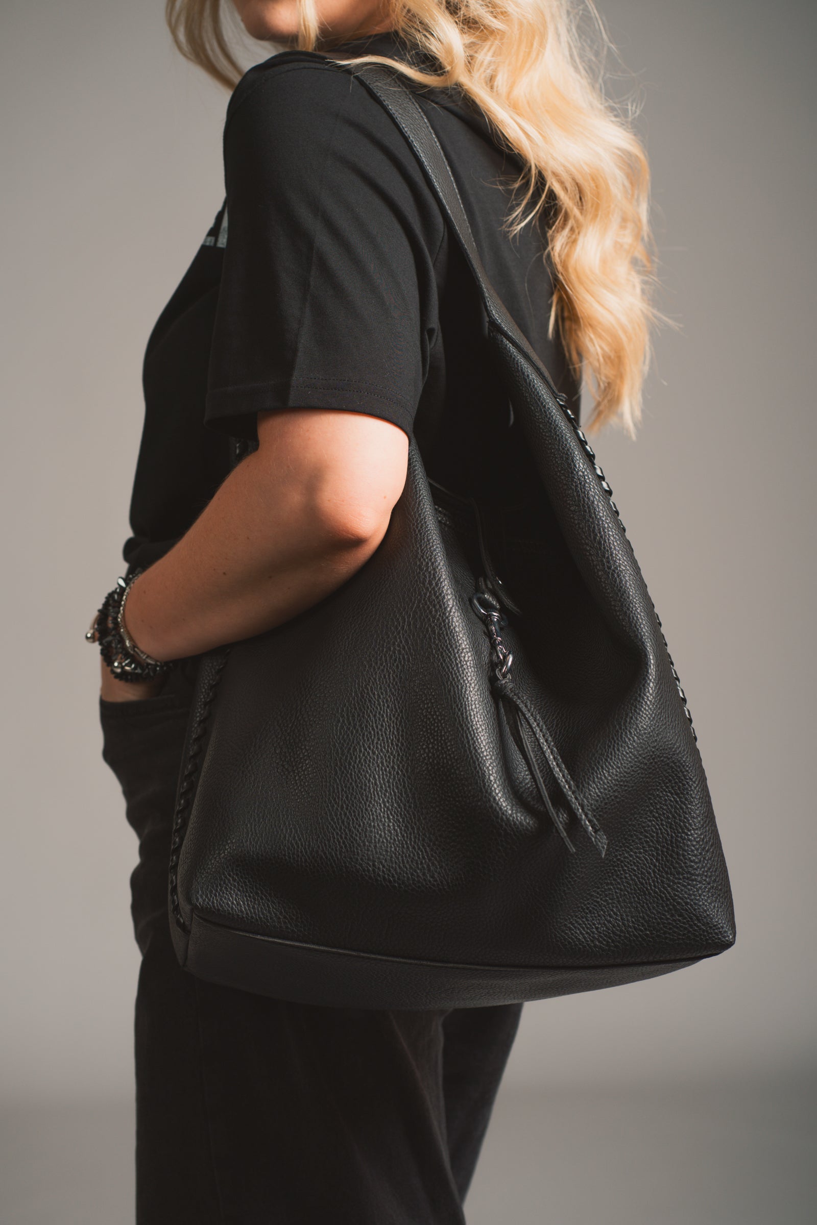 Model holding the Sadie Boho Hobo Faux Leather black bag, in studio shot.