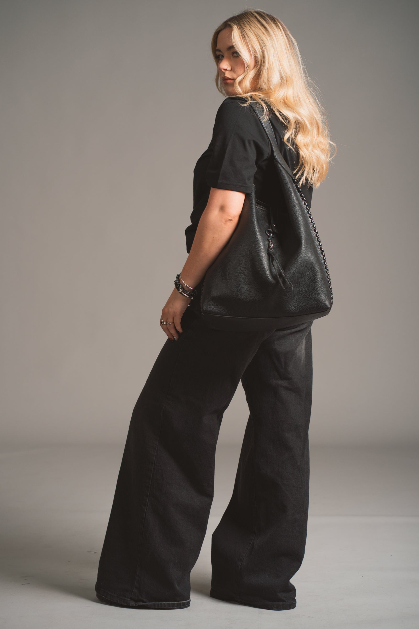 Model holding the Sadie Boho Hobo Faux Leather black bag, in studio shot.