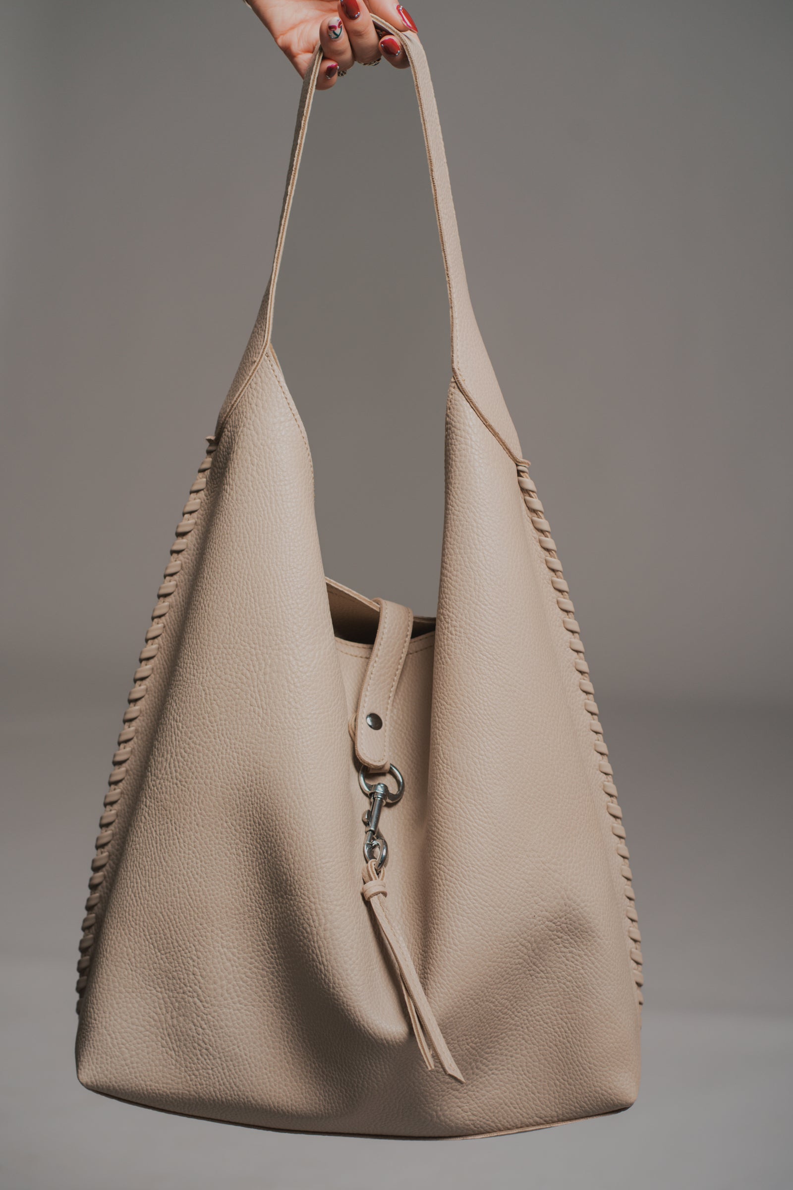 Sadie Taupe Faux Leather Hobo handbag held by a model against a neutral background