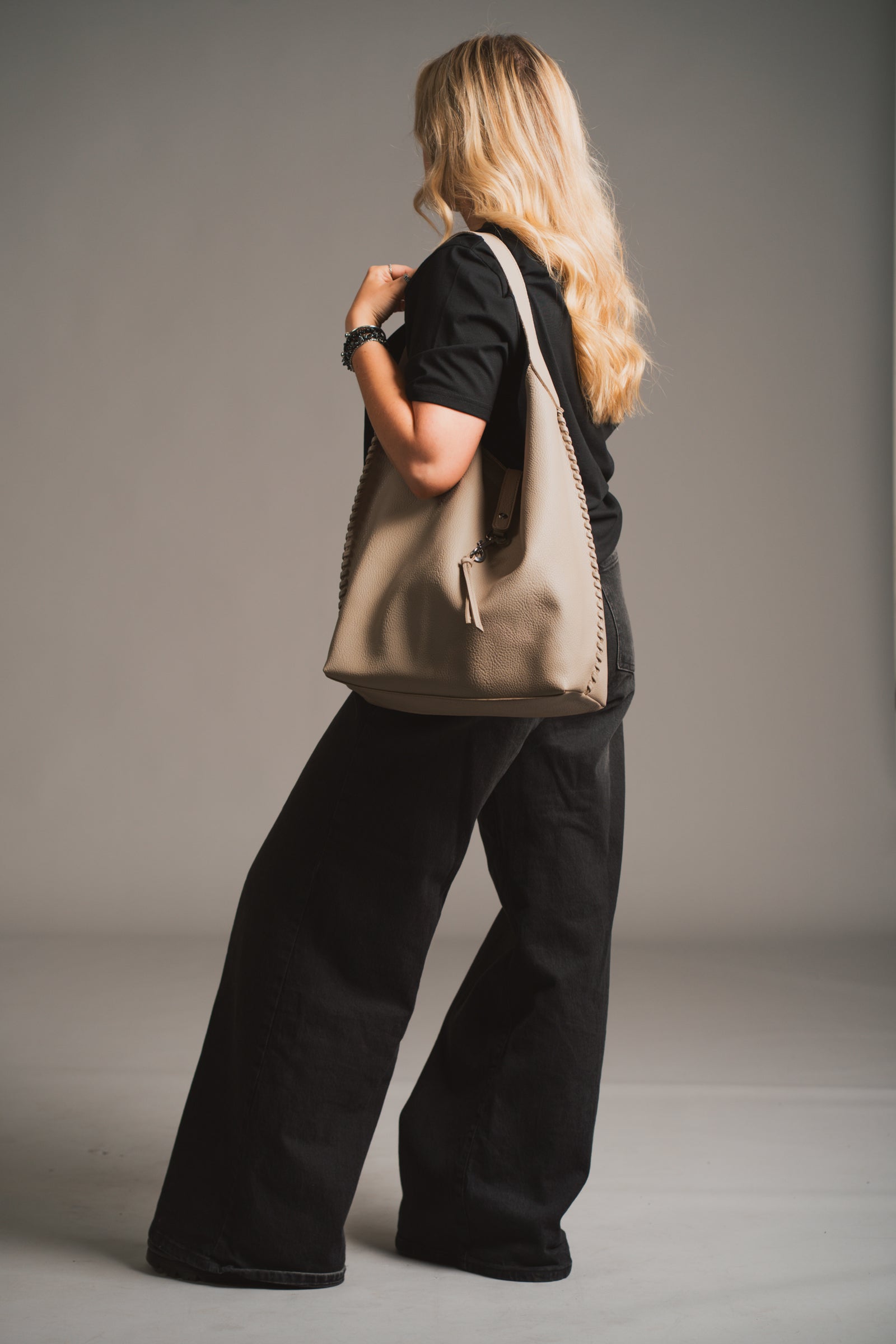 Sadie Taupe Faux Leather Hobo handbag held by a model against a neutral background