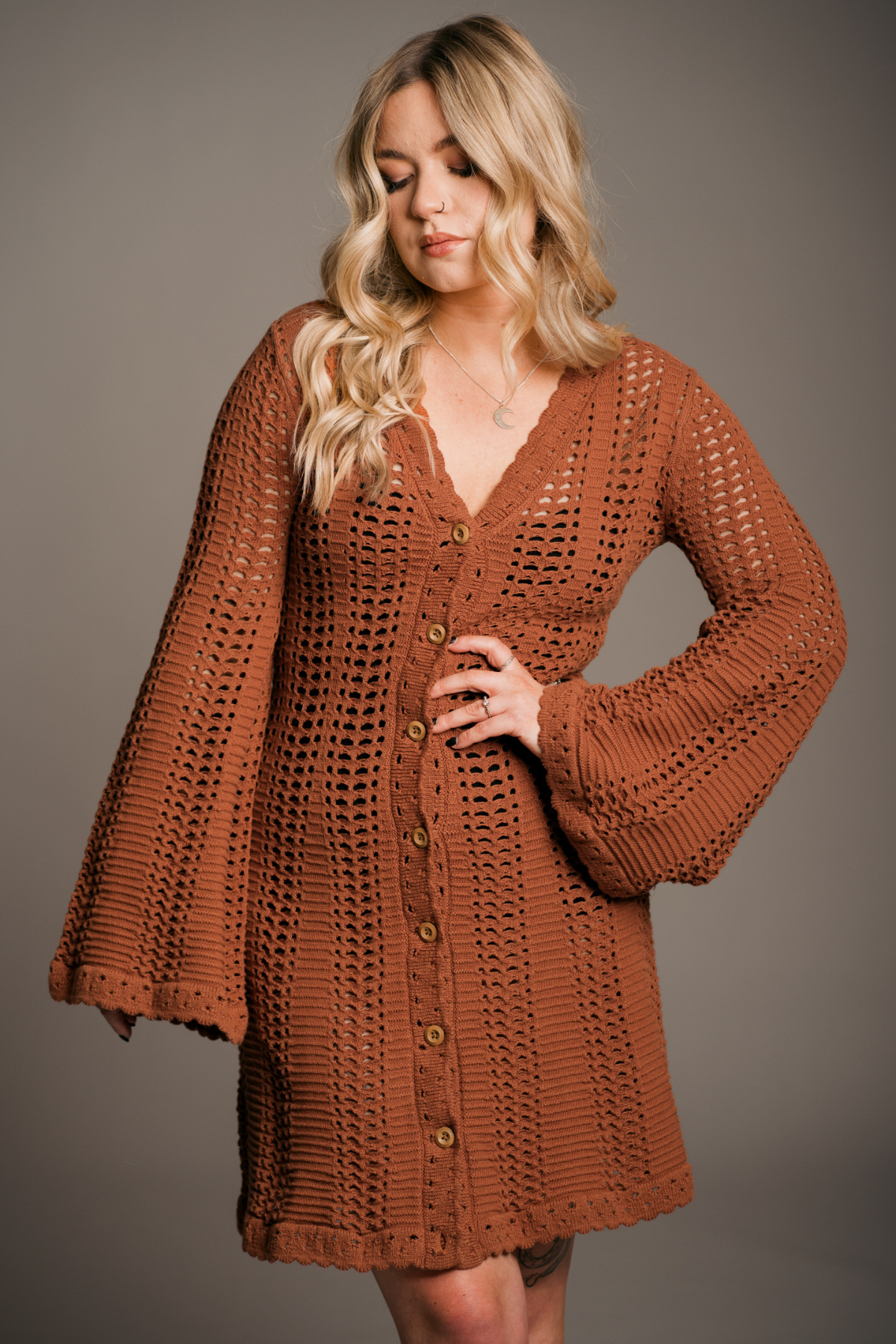 Model Erin in front of a neutral background wearing the Bohemian Marianne Rust Knitted Crochet Mini Dress.