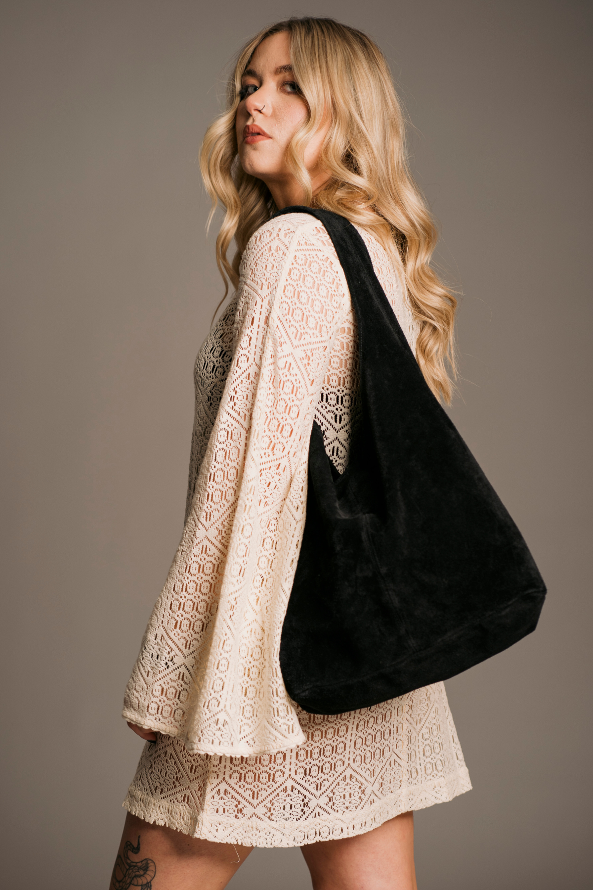 Model Erin on set wearing Goldie Ivory crochet Mini Dress styled with the Olsen Black slouchy Suede Bag