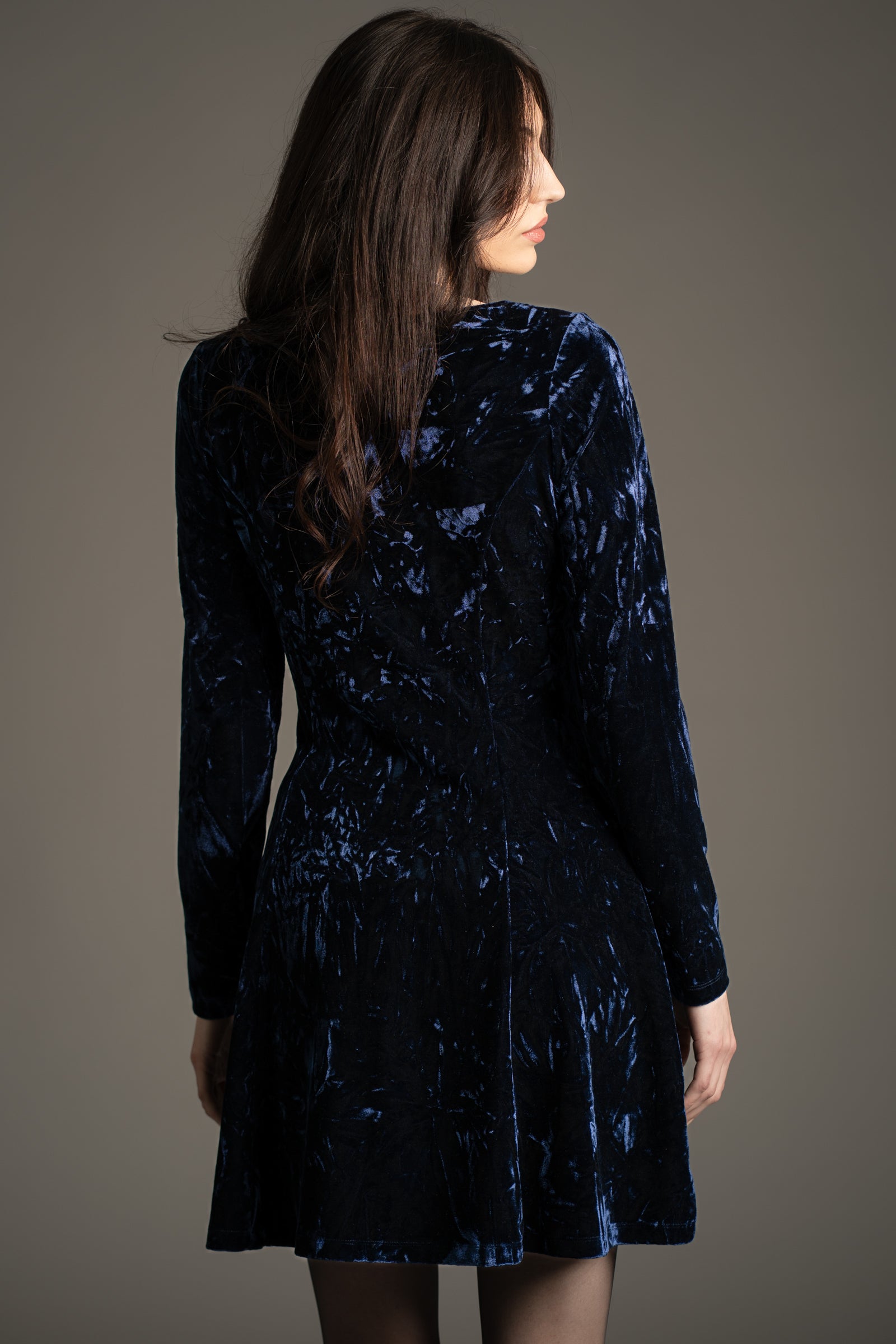 Back view of Little Lies Sweet Jane Midnight Crushed Mini Dress in deep blue velvet, long sleeves, studio setting