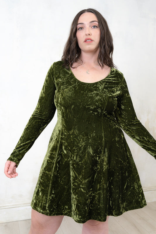 Taylor wearing the Sweet Jane olive crushed velvet mini dress As worn by Taylor Swift, with long sleeves and a scoop neckline.