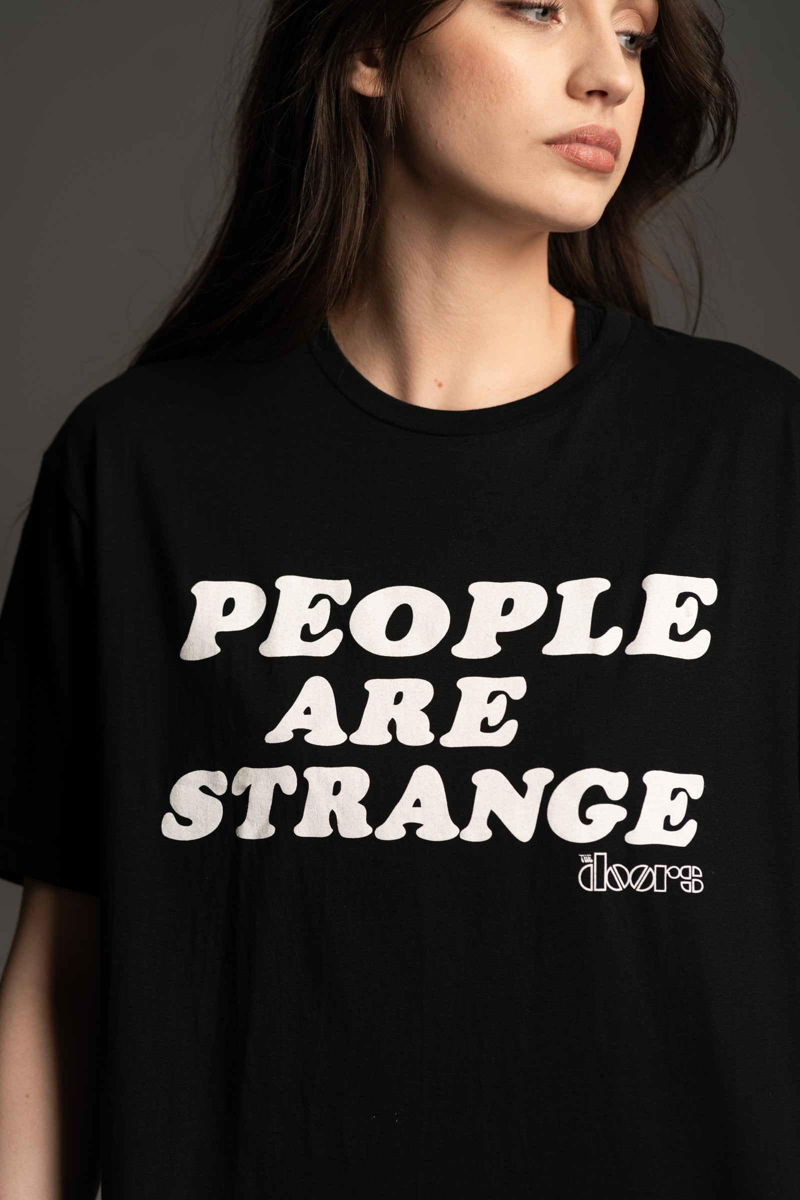Close up of Andie wearing Little Lies The Doors black graphic t-shirt with 'People Are Strange' slogan