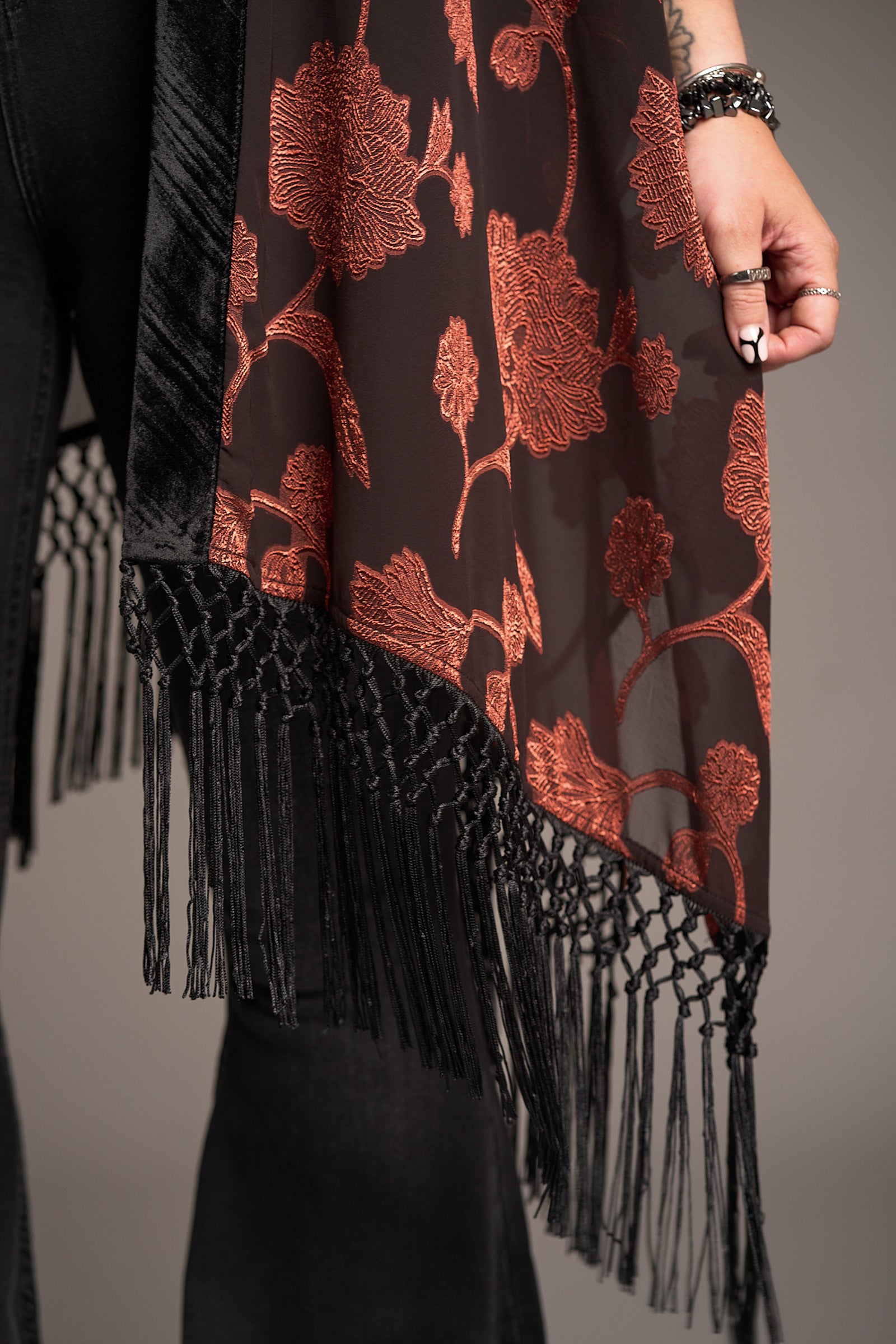Close-up of Venus Fringed Kimono with  sheer black fabric, red floral embroidery, and fringe detail