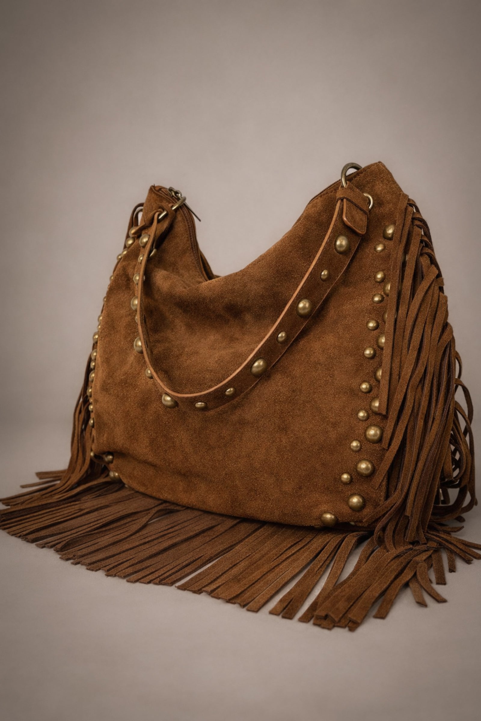 Little Lies Willow Slouchy tan faux suede bag with fringe and rivet detail in studio setting.