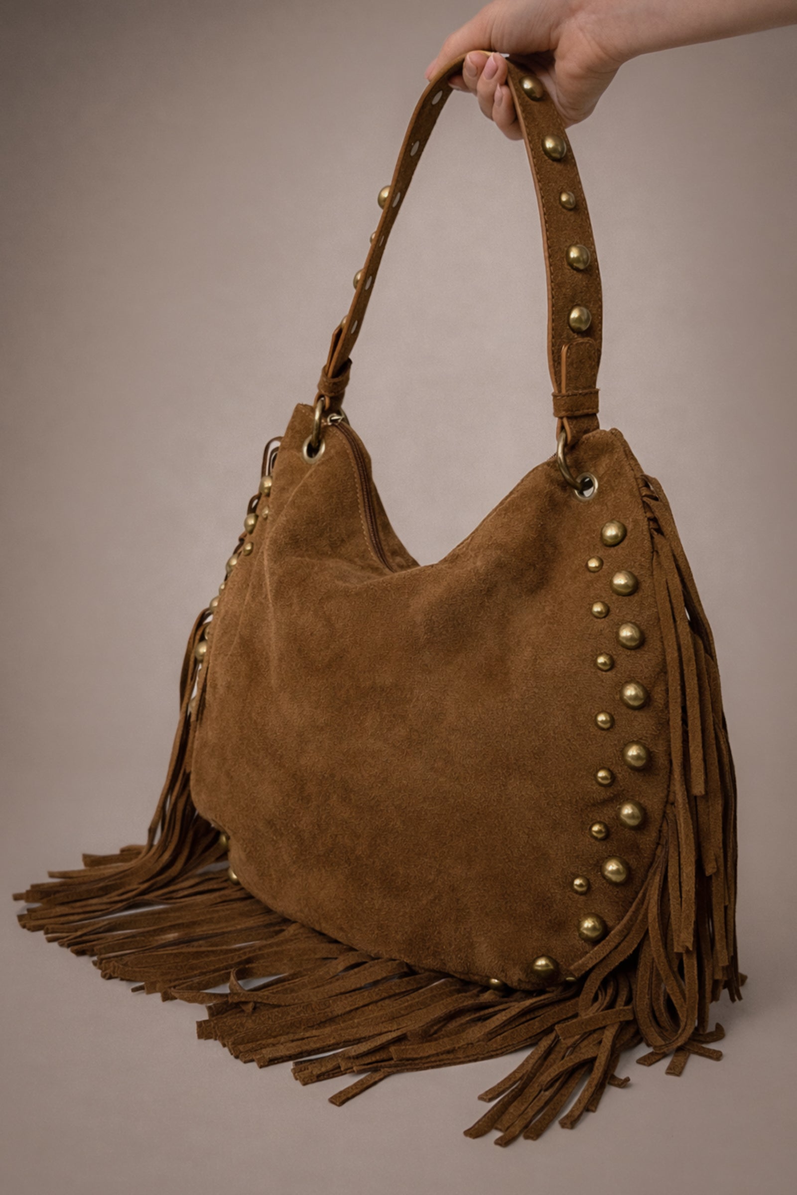 Little Lies Willow Slouchy tan faux suede bag with fringe and rivet detail in studio setting.