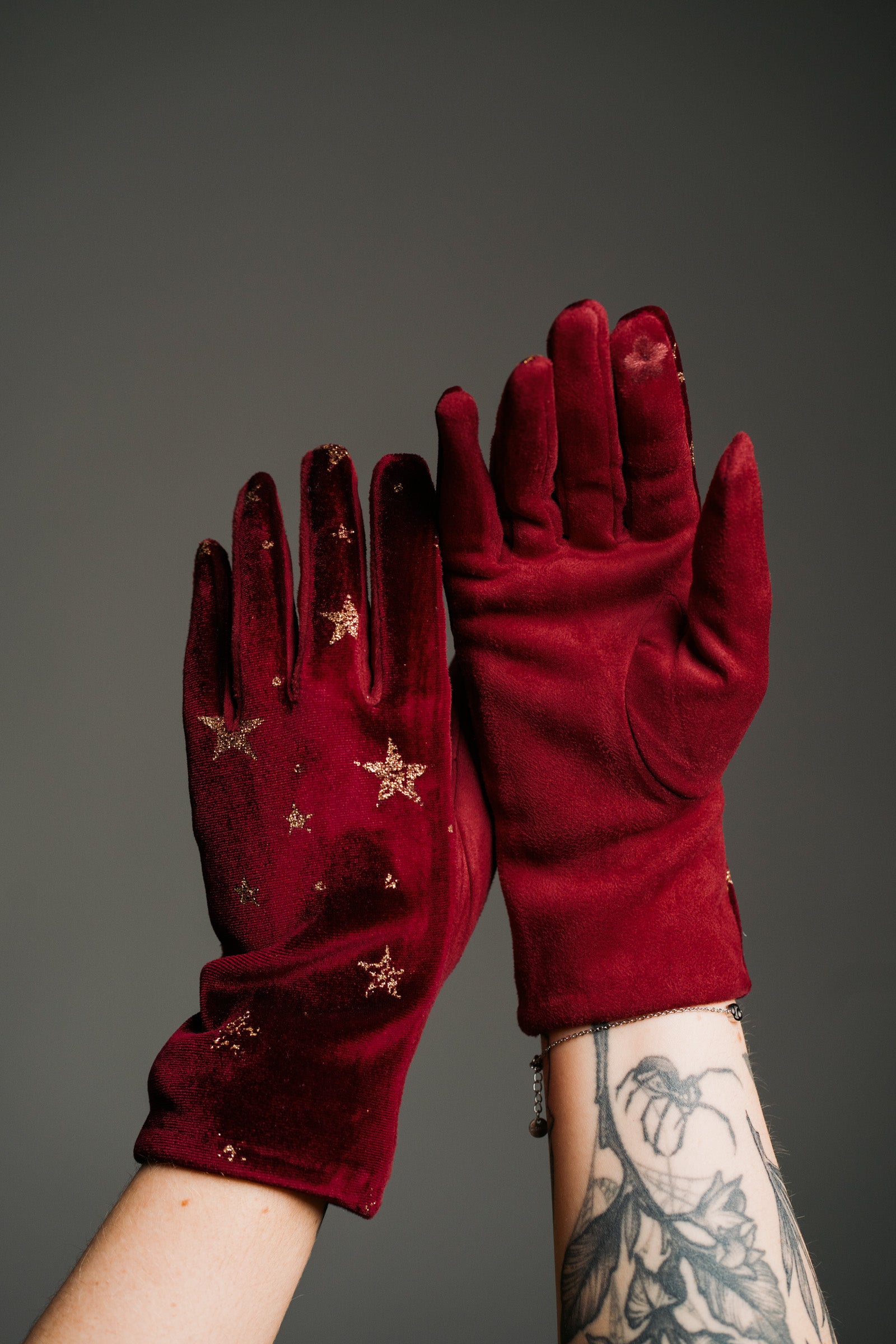 Product shot showcasing the Wine Velvet Celestial Gloves, with rich red fabric with gold star print detail and touchscreen friendly tip.
