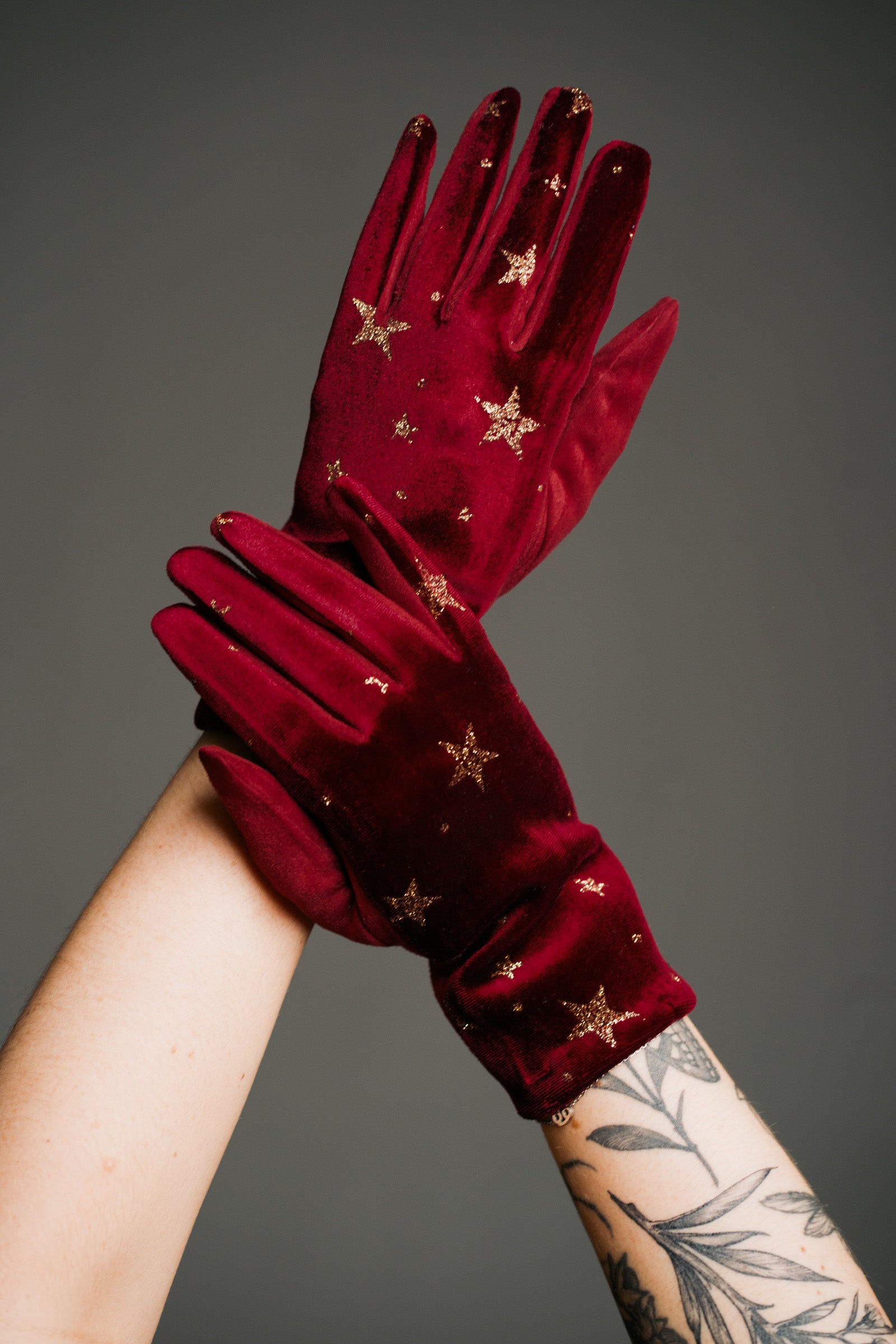 Product shot showcasing the Wine Velvet Celestial Gloves, with rich red fabric with gold star print detail.