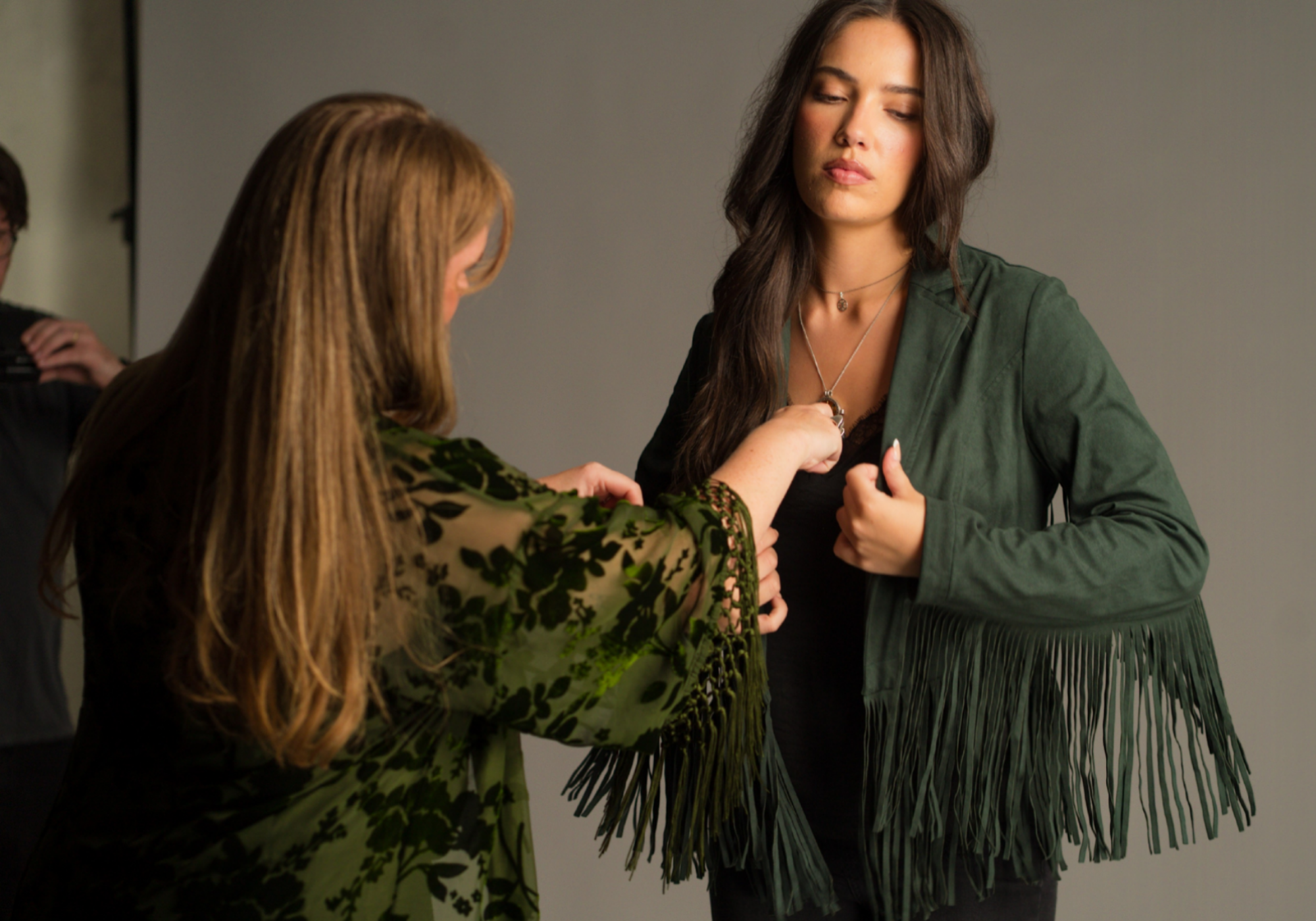 Jess wearing the emerald green Ivy faux suede fringe jacket being styled by Little Lies owner Jade in the studio.
