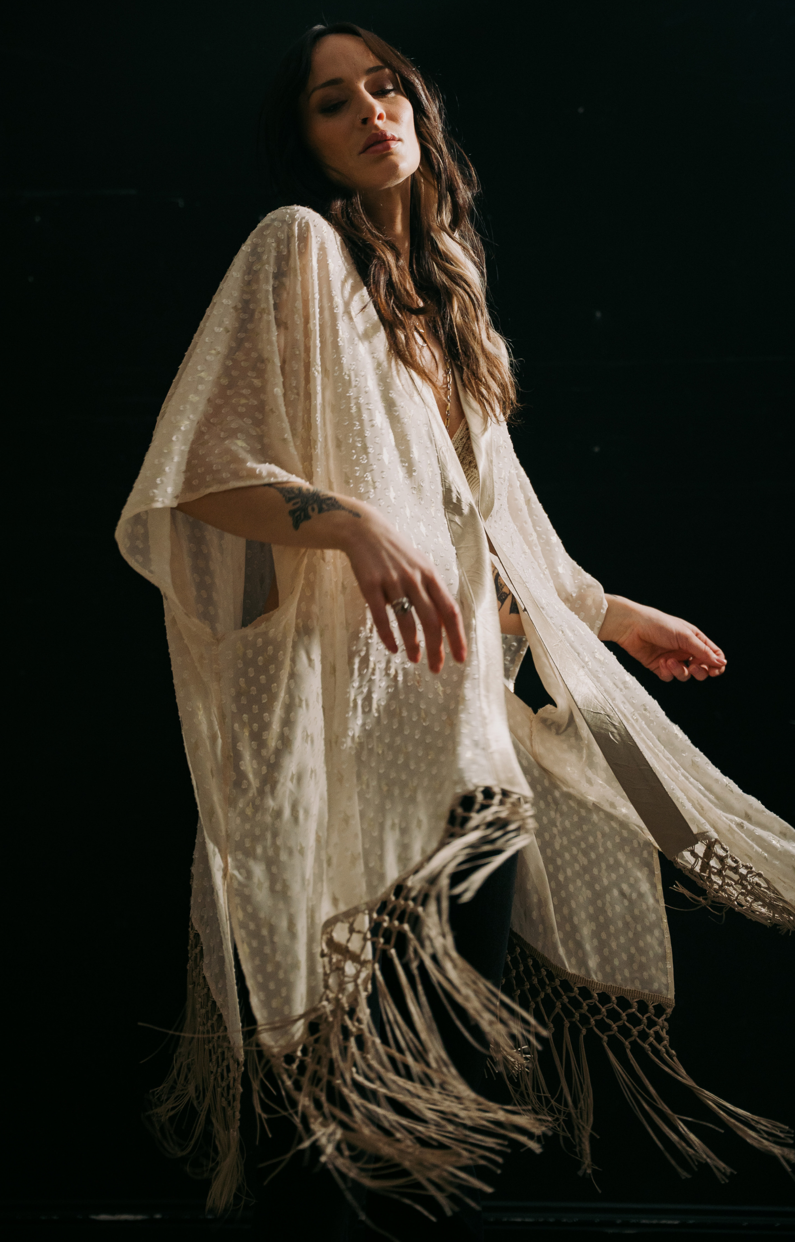 Model wearing the Little Lies Songbird Ivory Kimono featuring a soft ivory draped fabric with subtle textured detailing and long fringe trim.