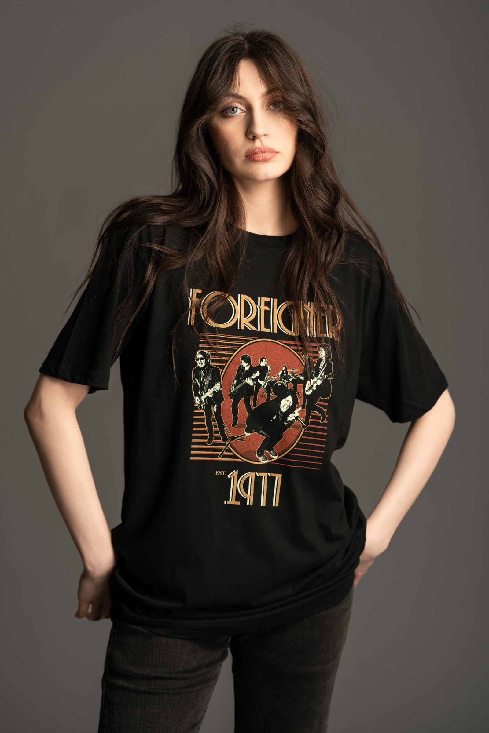Andie wears unisex standard fit black Foreigner 1977 graphic band t‑shirt by Little Lies, vintage-style rock tee.