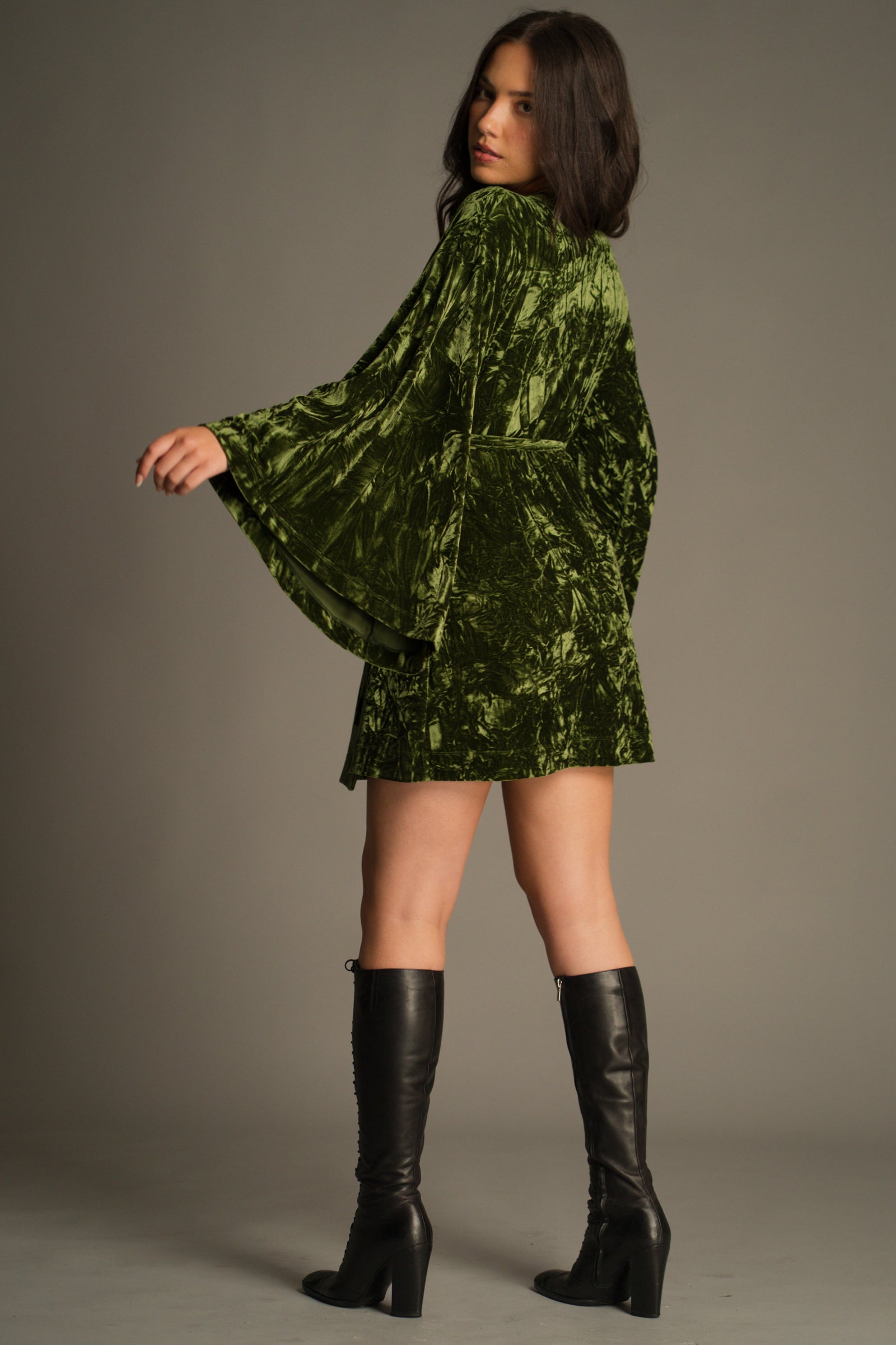 Back view of the crushed velvet texture and adjustable tie waist on the Jaded Olive Wrap Mini Dress.