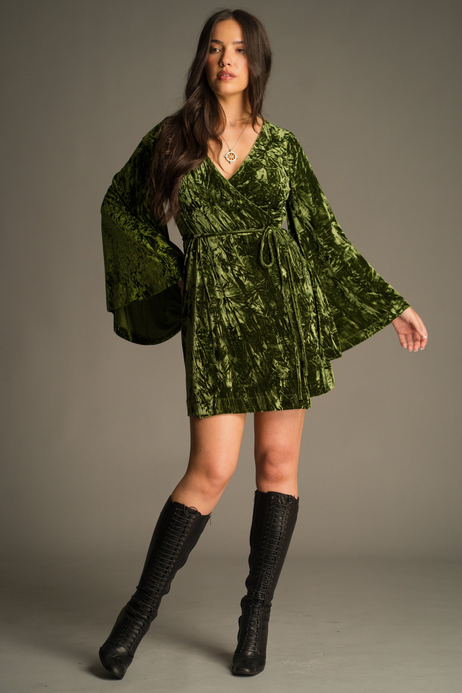 Front view of the Jaded Olive Crushed Velvet Wrap Mini Dress in rich mossy olive velvet. Styled with vintage YSL knee high boots.