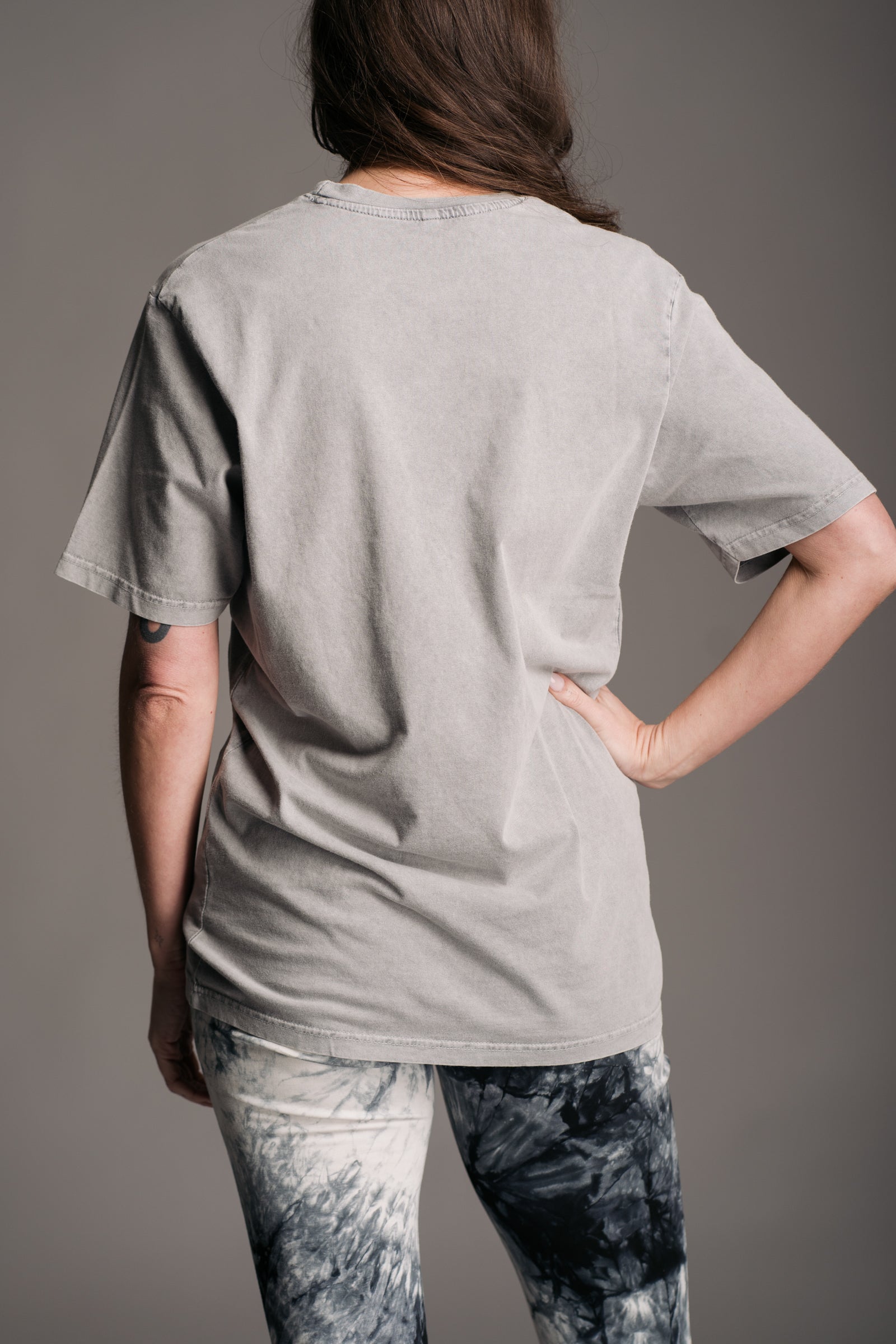 Plain back view of Little Lies grey acid‑wash Kurt Cobain band tee, styled with tie dye flares