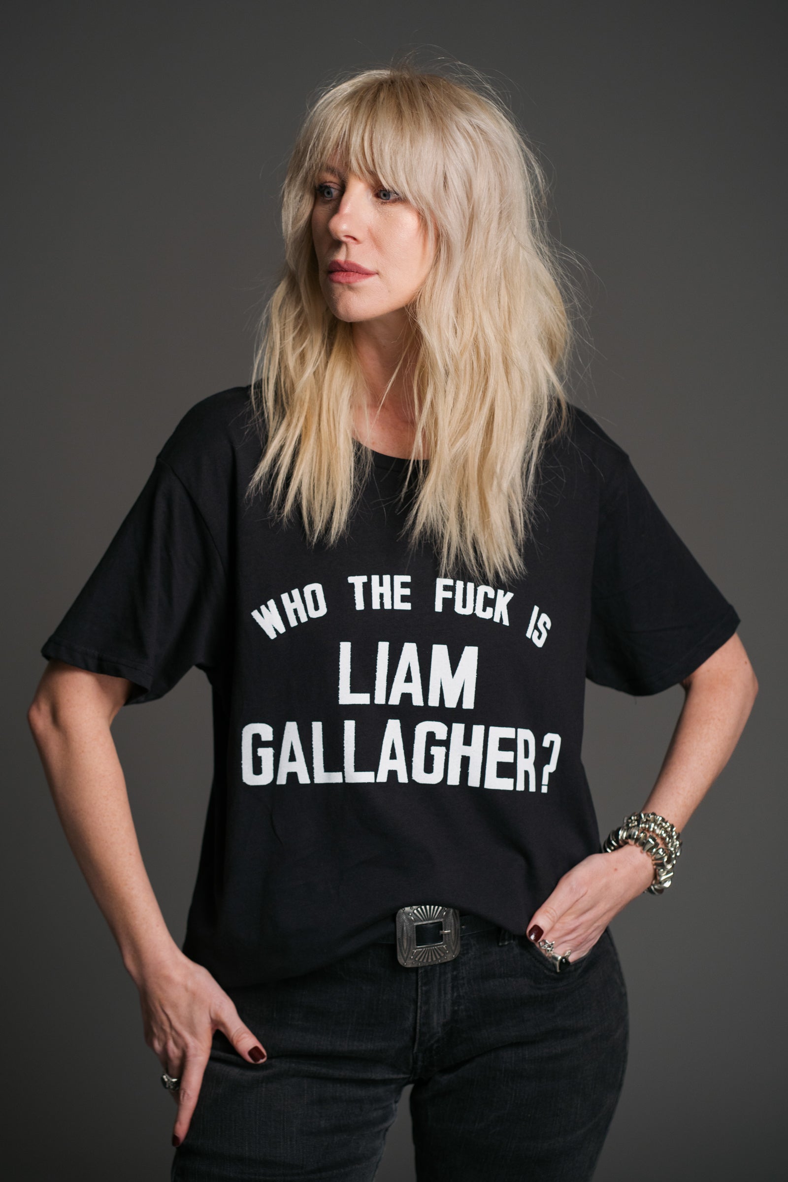 Sara wears black Liam Gallagher graphic slogan t‑shirt by Little Lies, relaxed fit rock tee styled with western belt and silver jewellery”