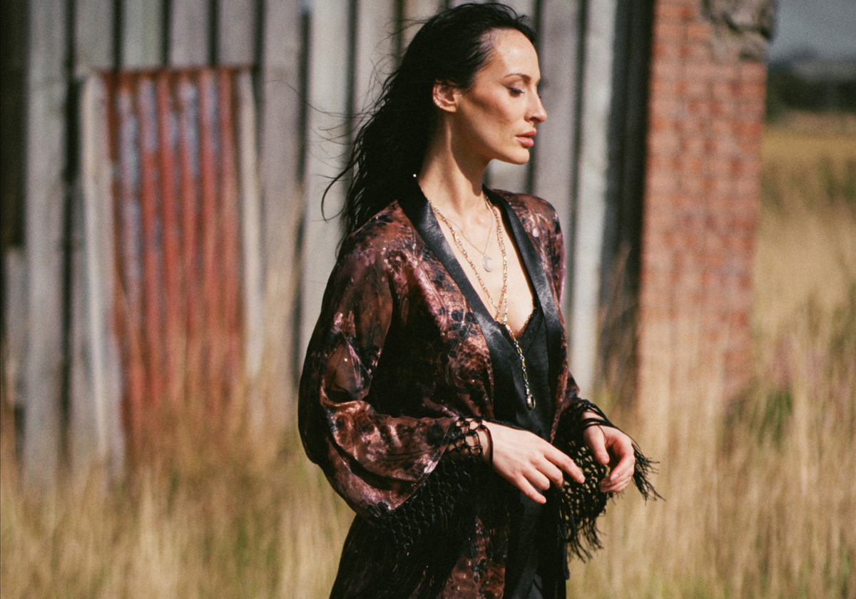 Model wearing the Little Lies Practical Magic Kimono in a Spellbound collection campaign shoot, featuring a celestial-inspired print and statement fringe detailing styled over a black lace slip dress.