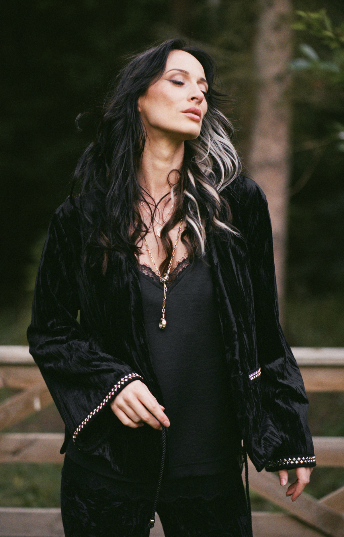 Model wearing the Little Lies Silver Springs Studded Velvet Jacket in a Spellbound collection campaign shoot, featuring black crushed velvet and silver stud detailing in a woodland setting.