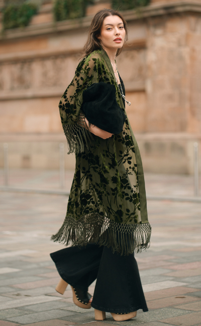 Dakota Olive Devore Kimono by Little Lies featuring velvet burnout detailing, fringe trim and a flowing bohemian silhouette styled with a suede bag and flared jeans