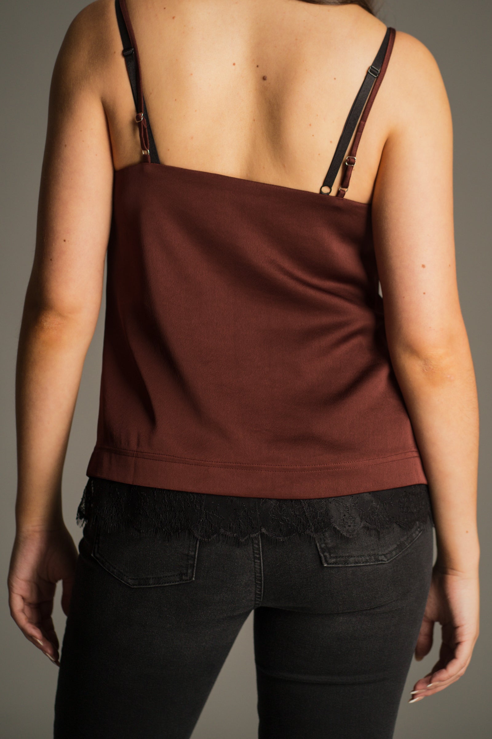Back view of the Nightbird Rust Satin Cami Top showing lace trim hem details.
