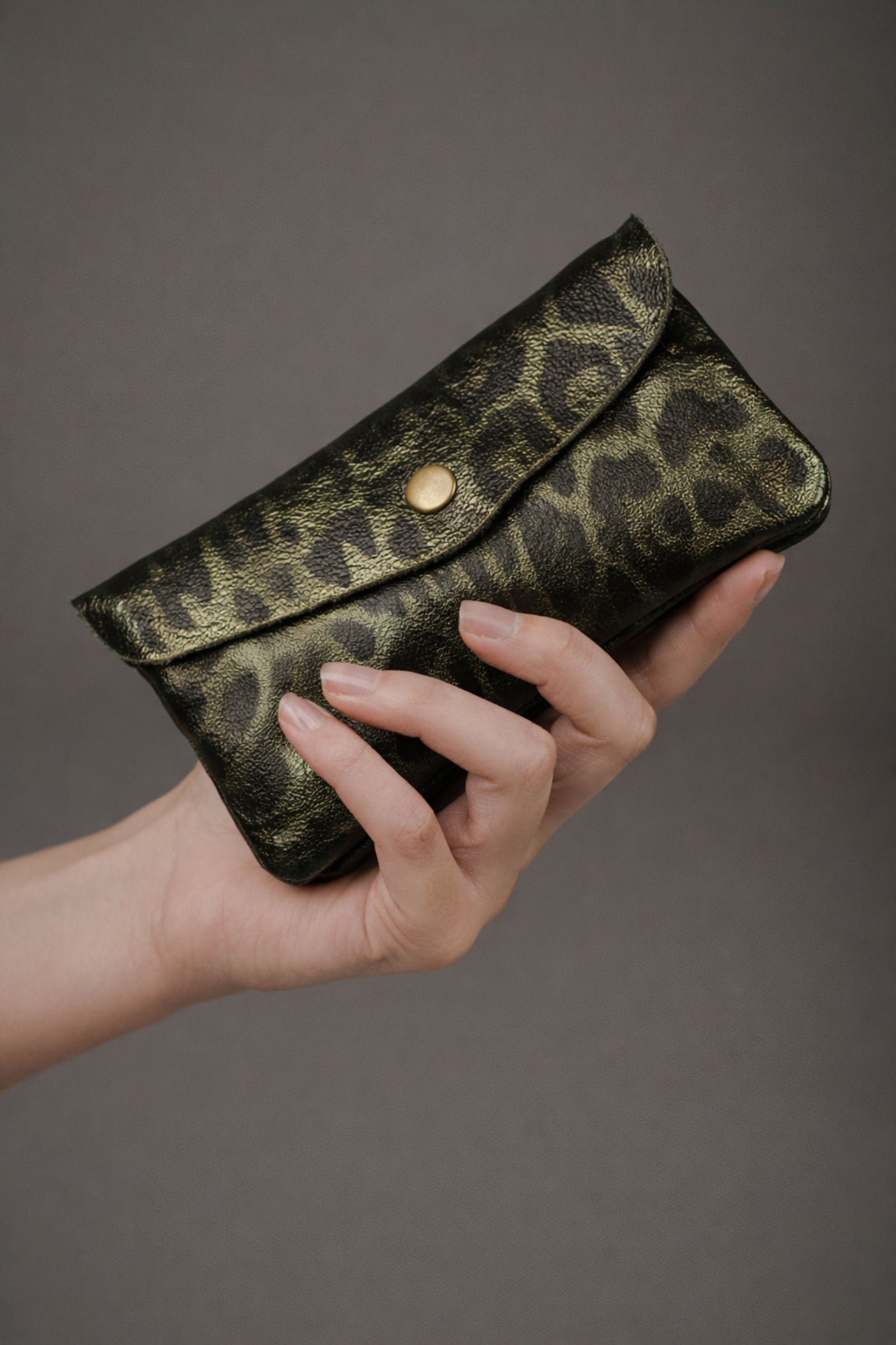 Olive metallic genuine suede purse with leopard print pattern held in a hand.