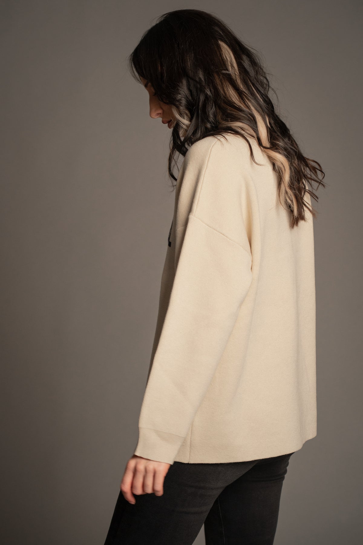 Victoria wearing the Rebel Rebel Cream Knit Jumper — side-back angle