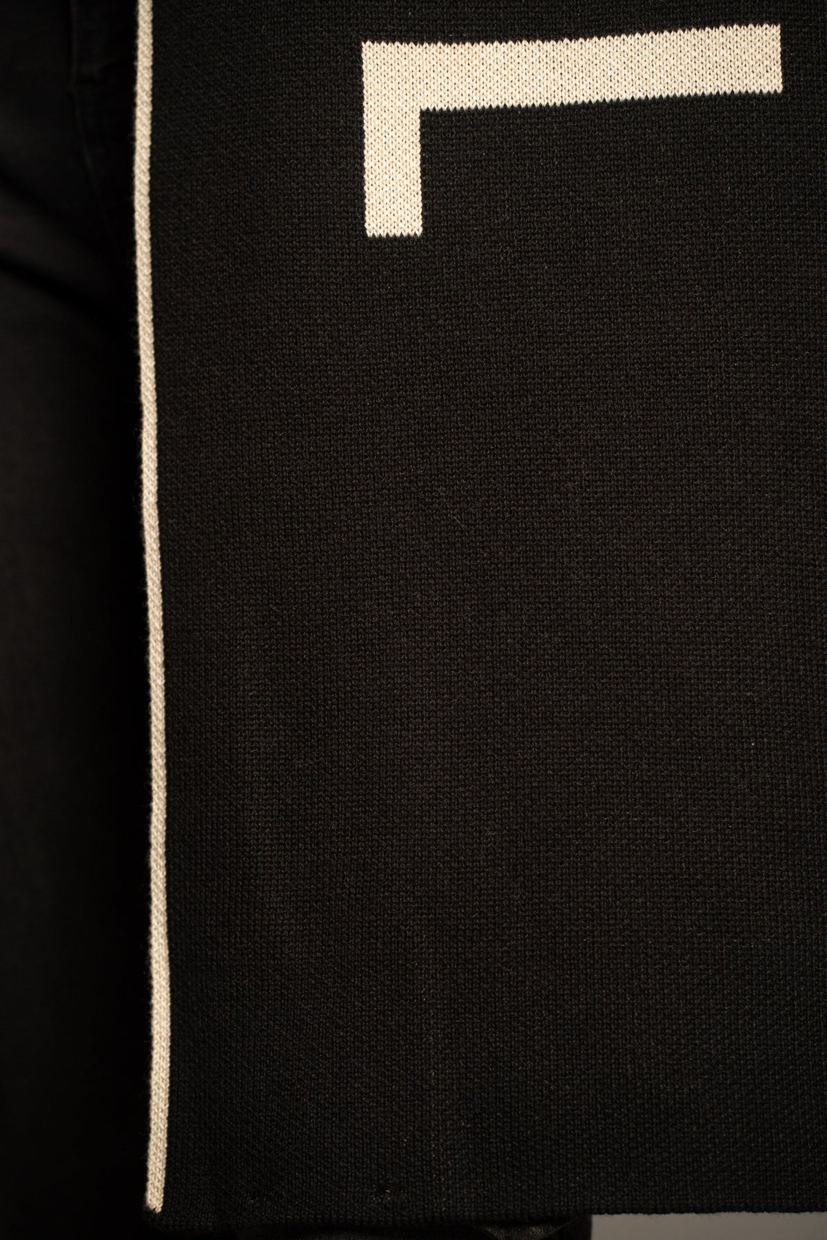 Close-up of the Little Lies Rebel Rebel Knit Scarf featuring ivory Rebel slogan lettering on a black knit background