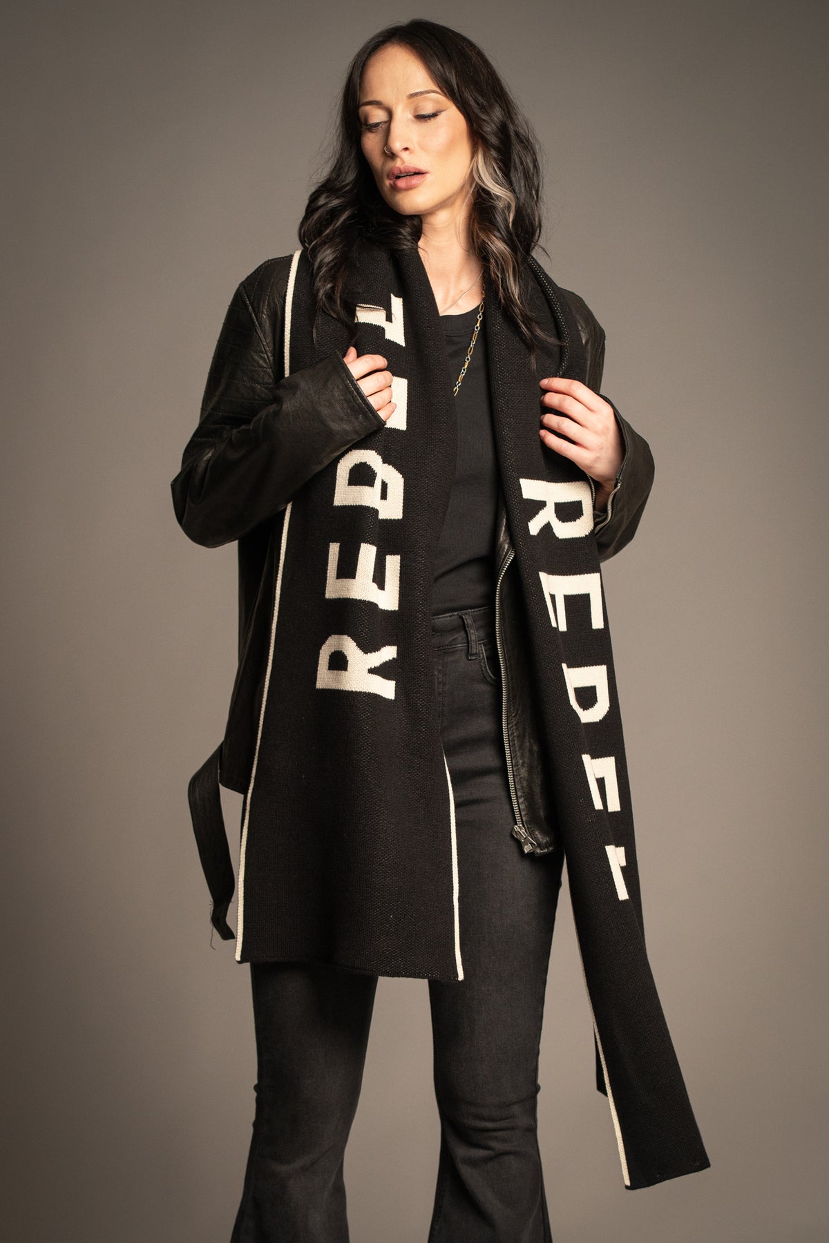 Model wearing the Little Lies Rebel Rebel Knit Scarf in black styled with a leather jacket and Hendrix denim flares