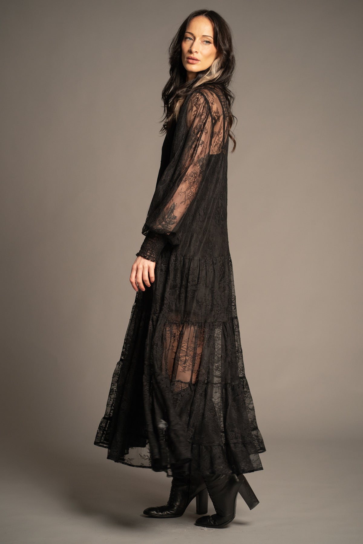 Rhiannon black lace maxi dress side view with sheer lace overlay, billowy sleeves and tiered skirt