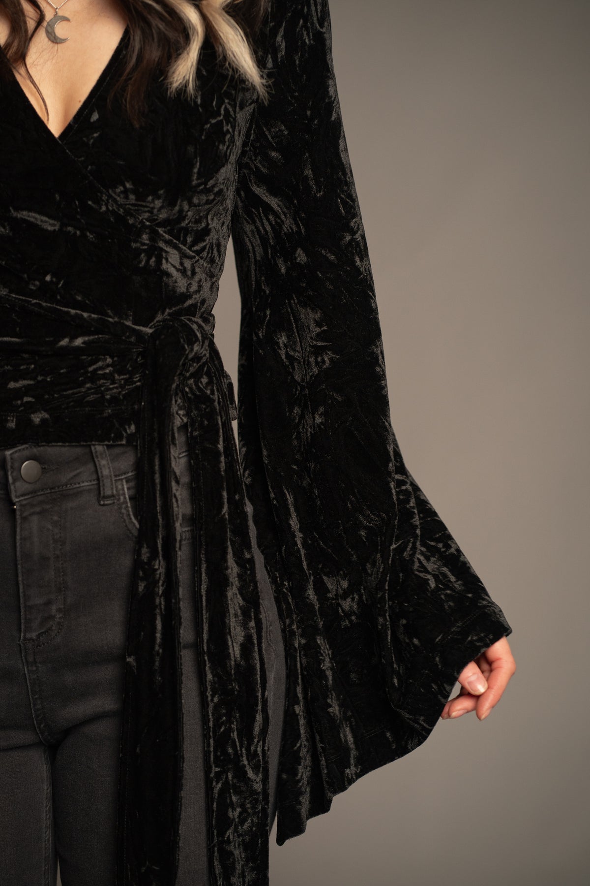 Sally black velvet wrap top detail featuring statement bell sleeve, waist tie and crushed velvet texture