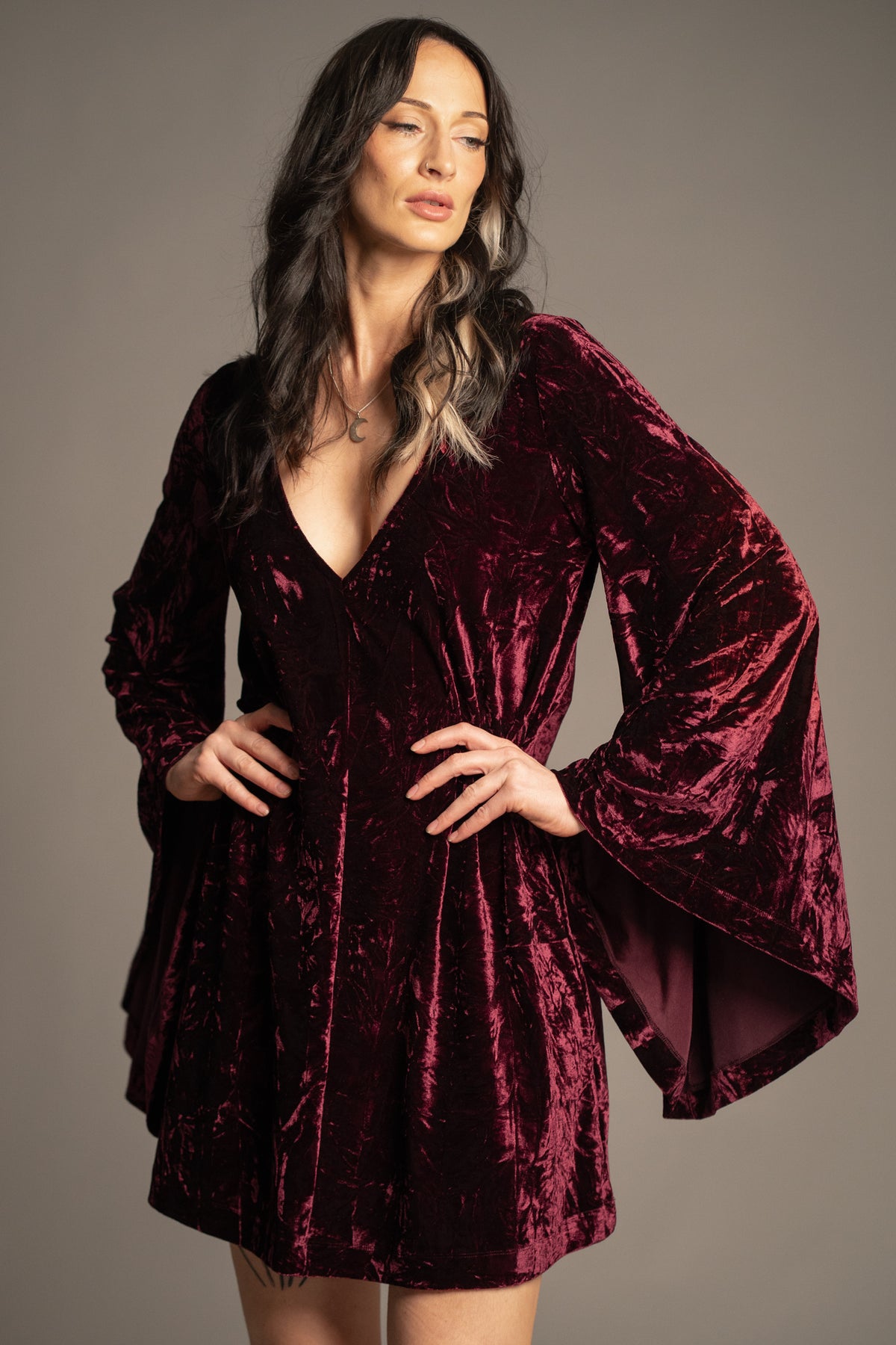 Close-up of Sara merlot velvet mini dress showcasing deep V-neckline, luxurious crushed velvet texture and bell sleeve detail