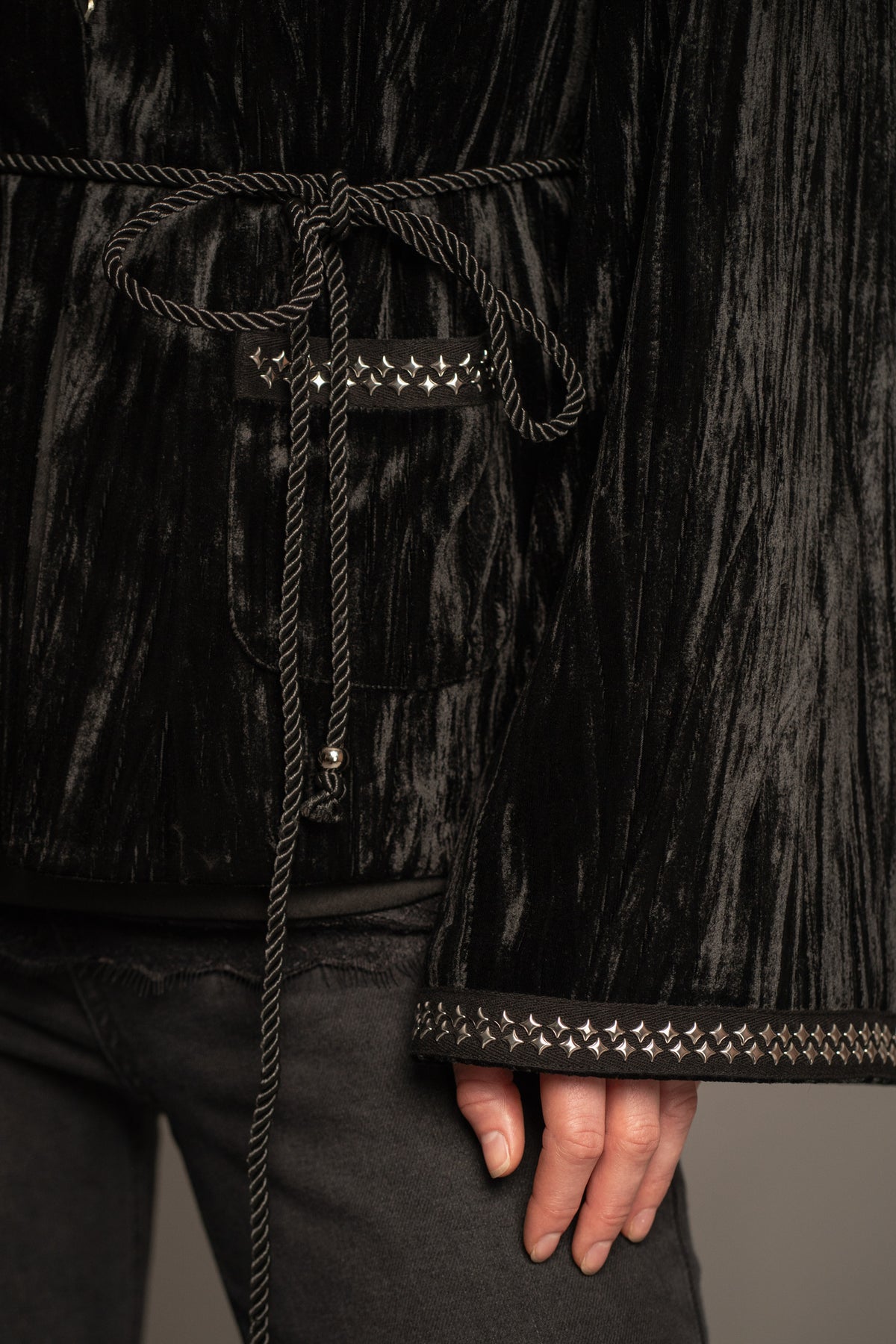 Close-up of Silver Springs studded velvet jacket showcasing  luxurious crushed velvet texture with silver stud trim cuffs, pockets and beaded rope tie-belt detail