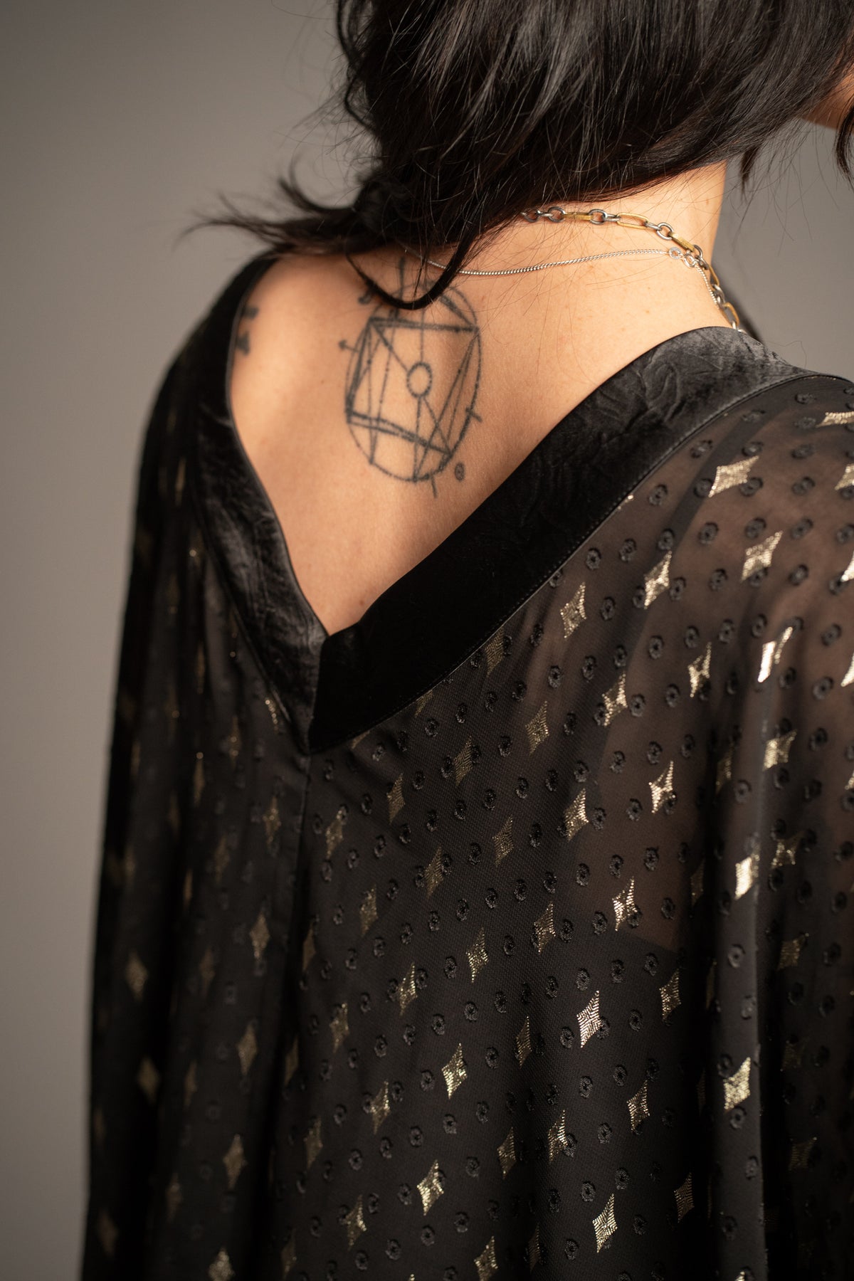 Close-up of Songbird black metallic kimono showcasing gold foil star print, sheer fabric and contrast trim neckline