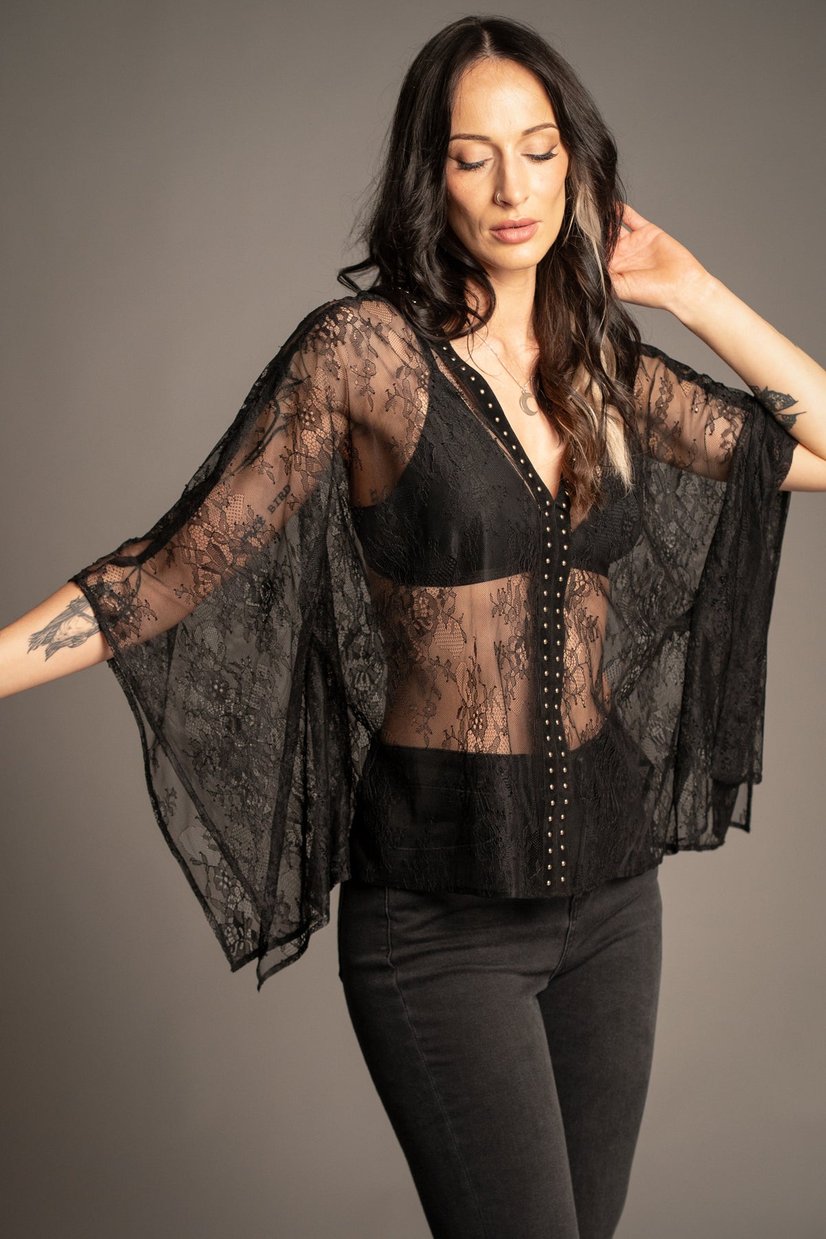 Spellbound studded lace kimono top styled with black flared jeans, featuring sheer floral lace and gold stud detailing