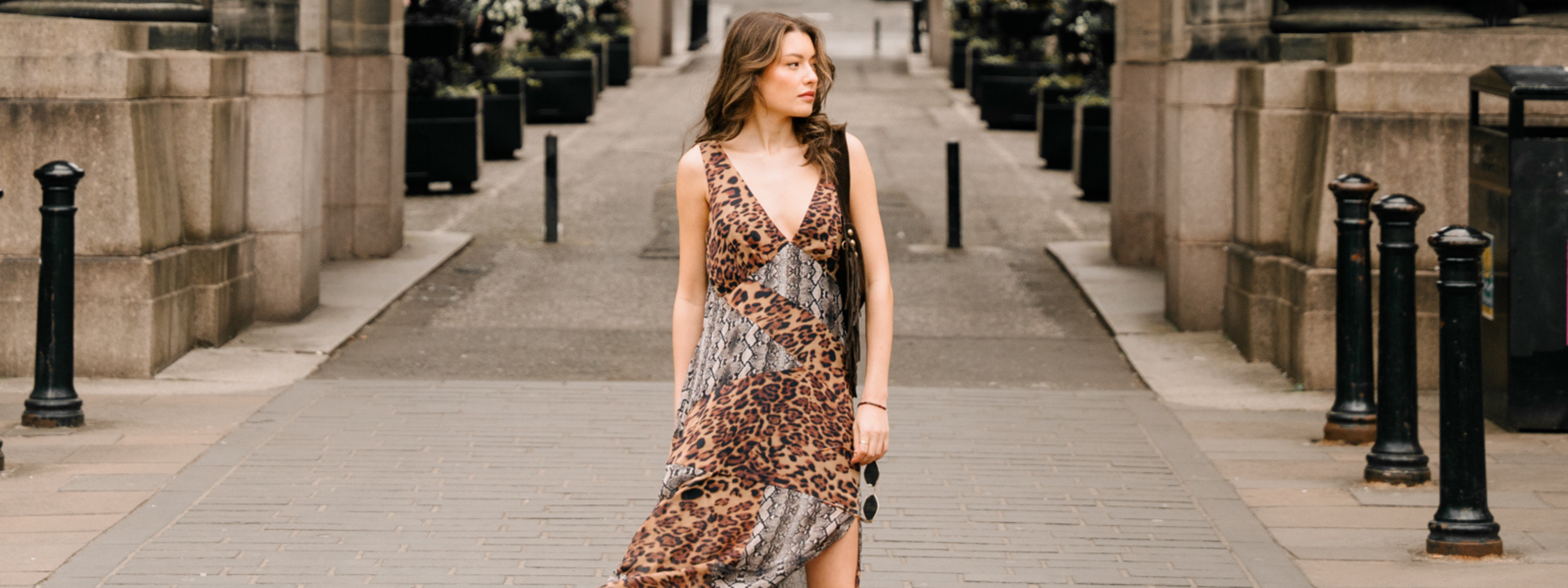 Model wearing Zadie Animal Handkerchief Dress. Leopard and Snake Print with fringed brown bag and shades.