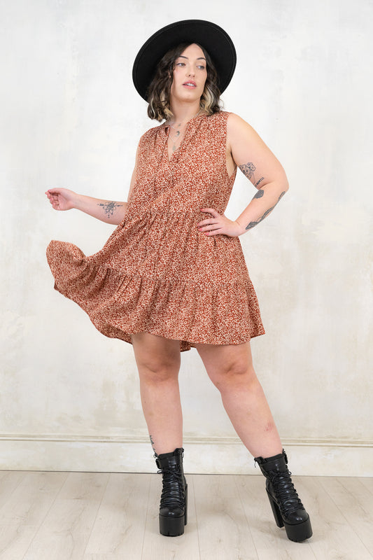 Model wearing Landslide Rust Smock - Rust and cream ditsy floral print,  sleeveless smock dress with a tiered a-line skirt and plunge neckline 