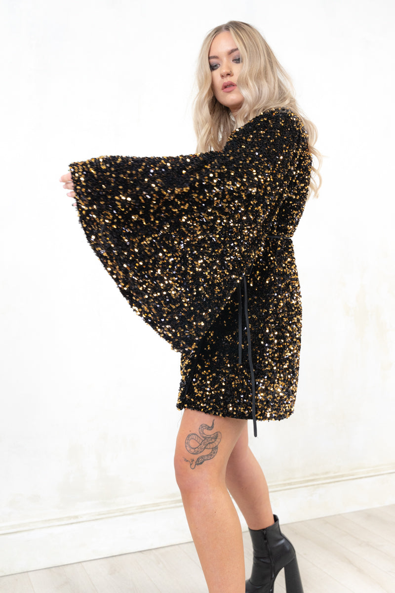 Model wearing Killer Queen Gold Sequin Wrap Dress, a Gold Sequined Velvet True wrap front dress with flared sleeve and deep V-neck